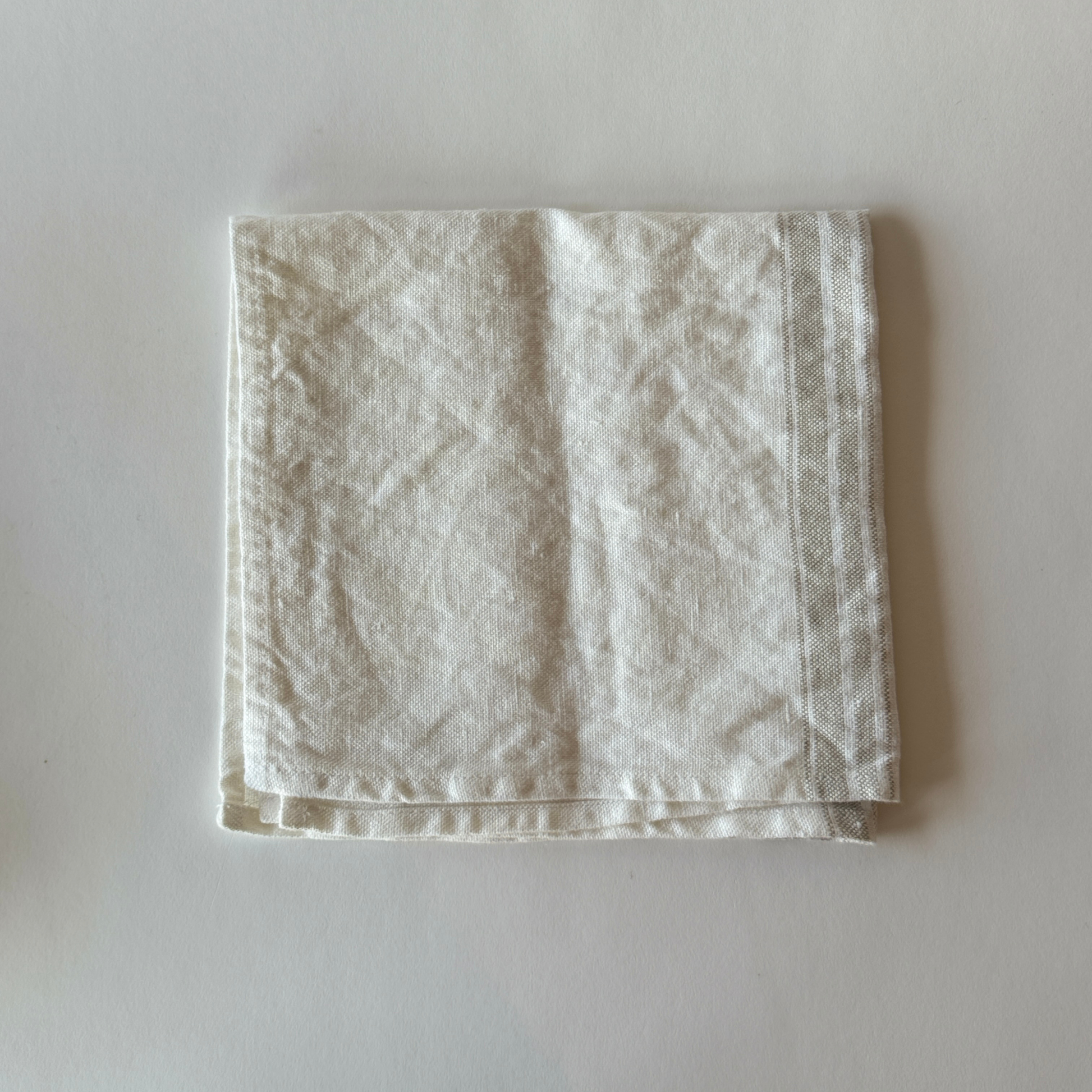 A Linen Way - Maison Table Napkin by Grace & Company, neatly folded on a light, plain surface.