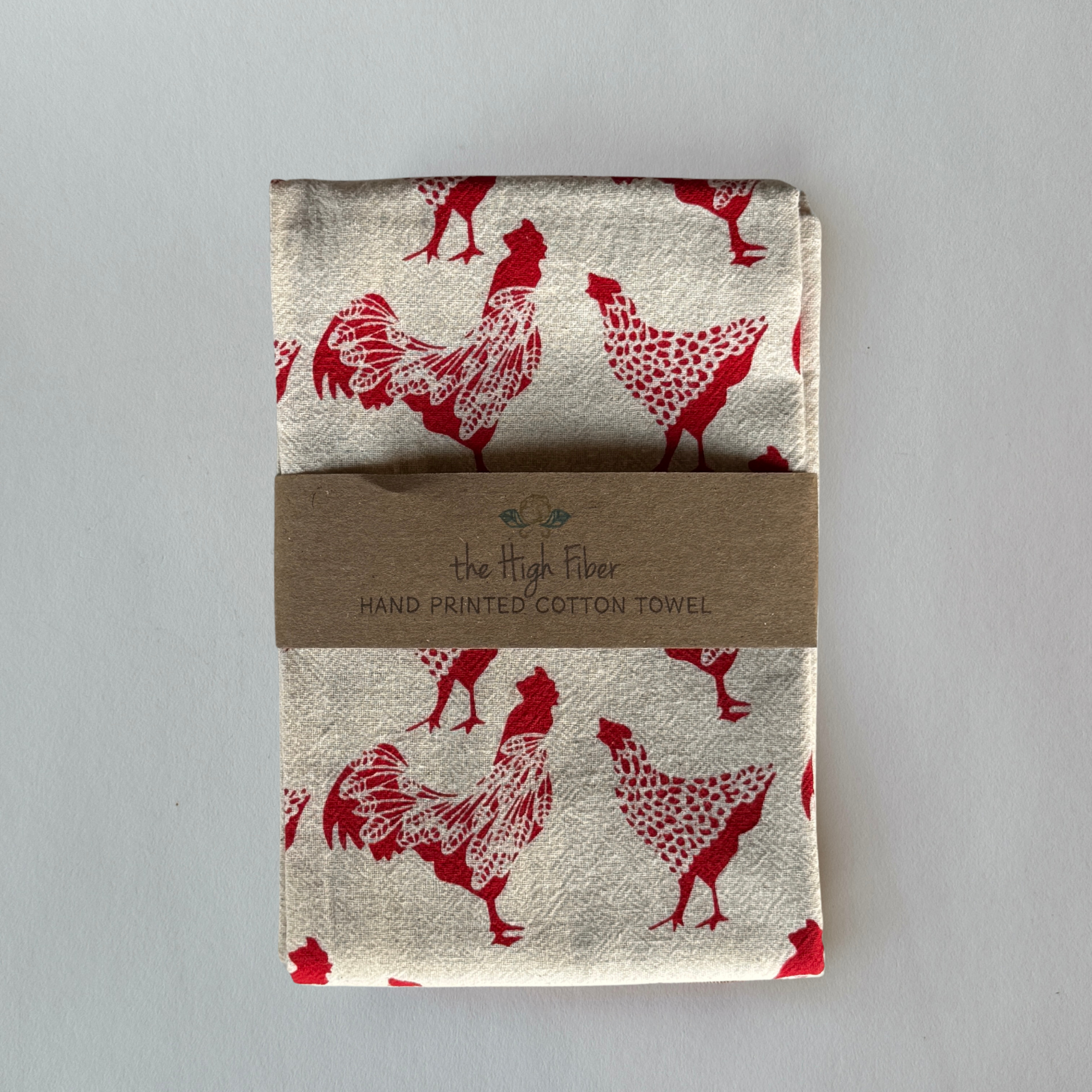 A folded cotton towel by Grace & Company with red chicken prints, labeled Hand Painted Cotton Towel.