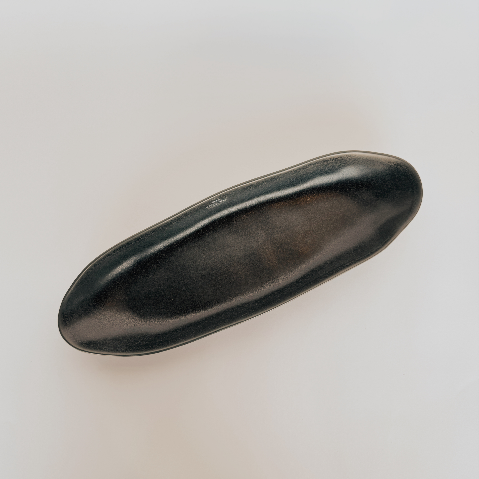 The Costa Nova Graphite Oval Platter by Grace & Company features curved edges on a plain, light background.