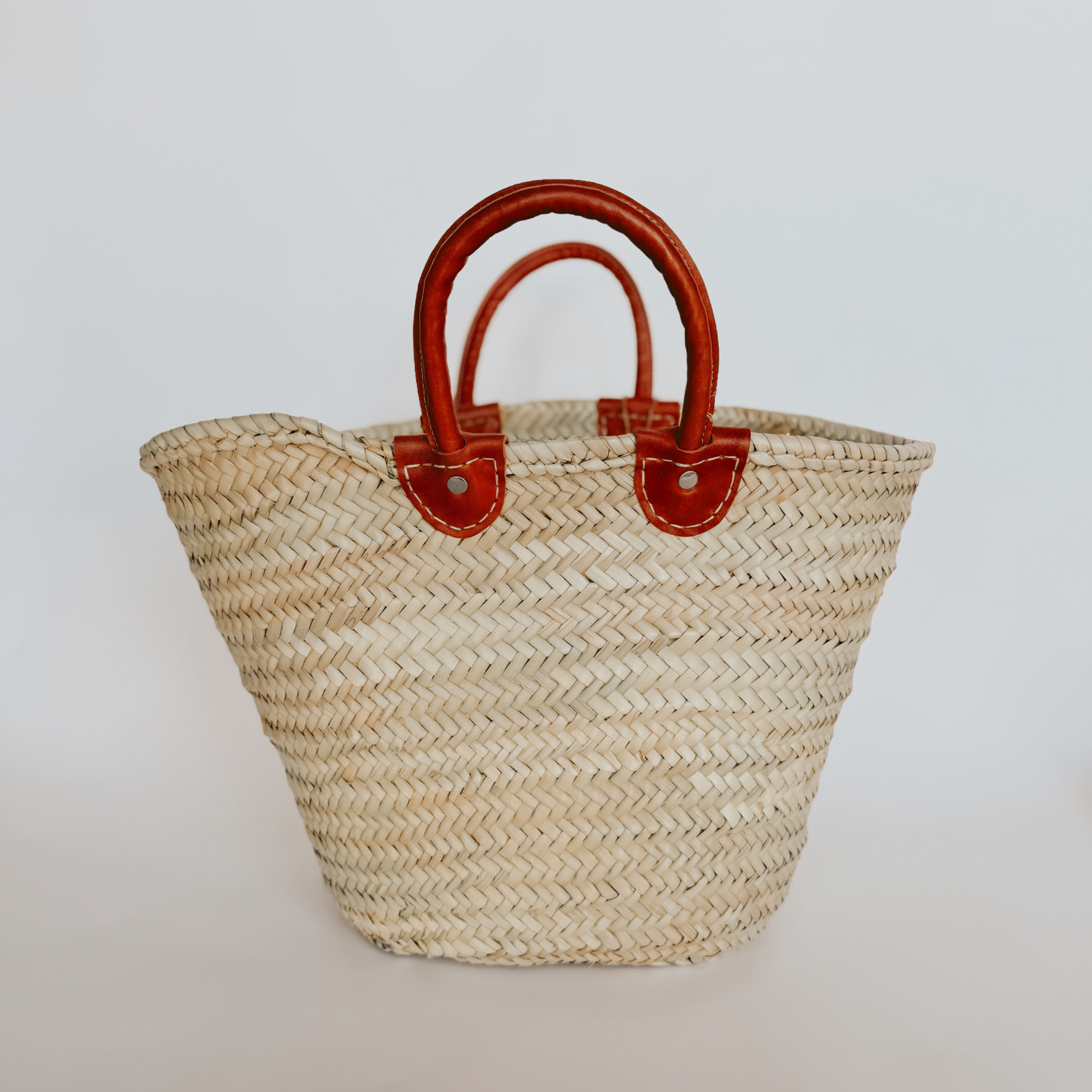 The French Bag - Agathe by Grace & Company ltd, a woven straw tote with brown leather handles on white background.