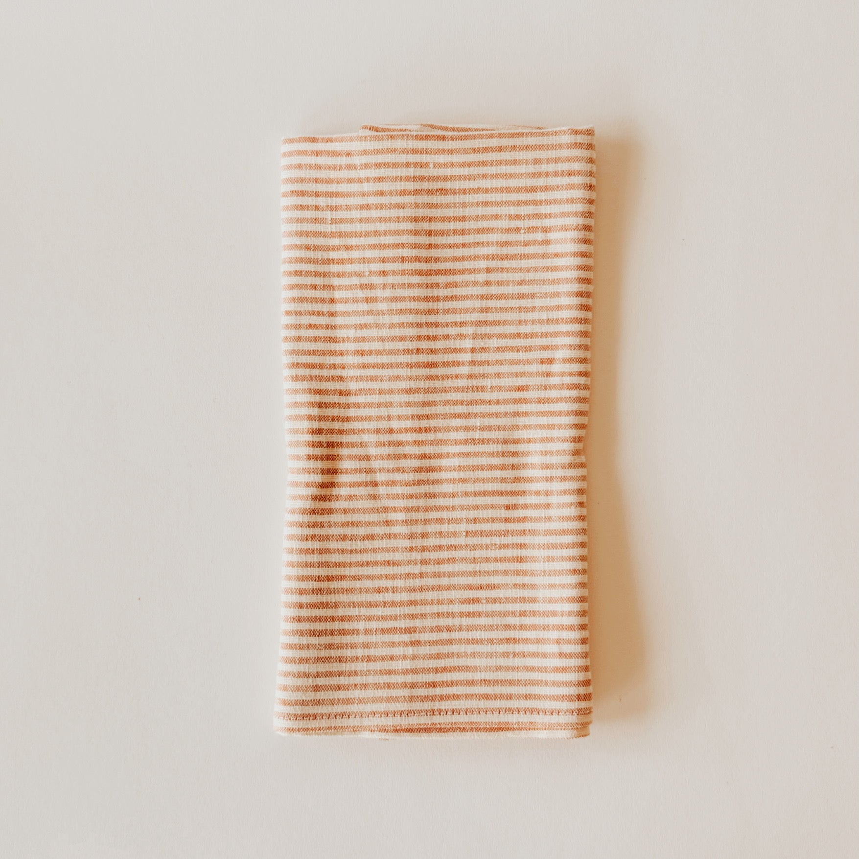 Grace & Company Linen Way - Red Picnic Kitchen Cloth with thin red stripes, folded on a white background.