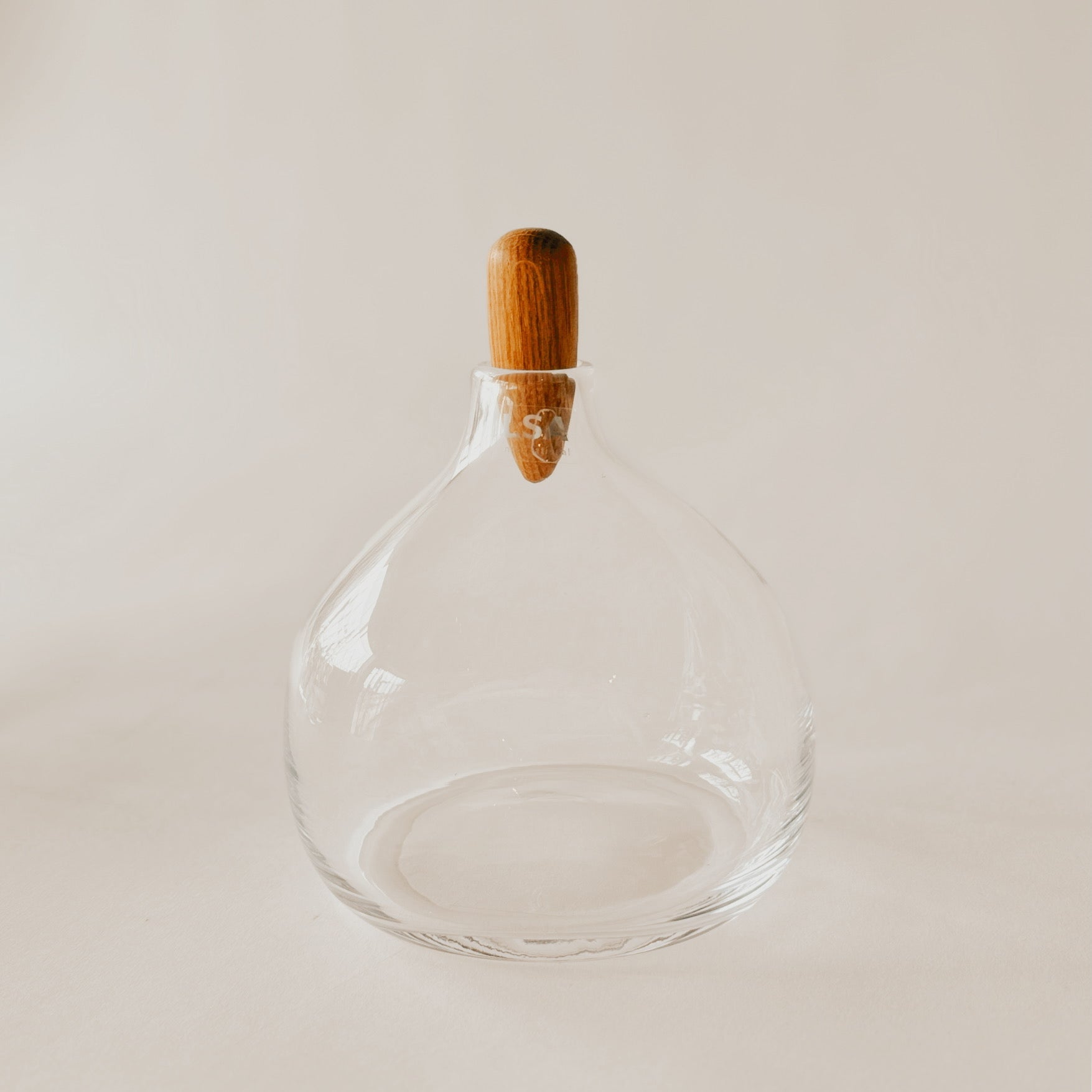 The LSA Float Decanter with oak stopper by Grace & Company features a rounded base on a light, plain background.