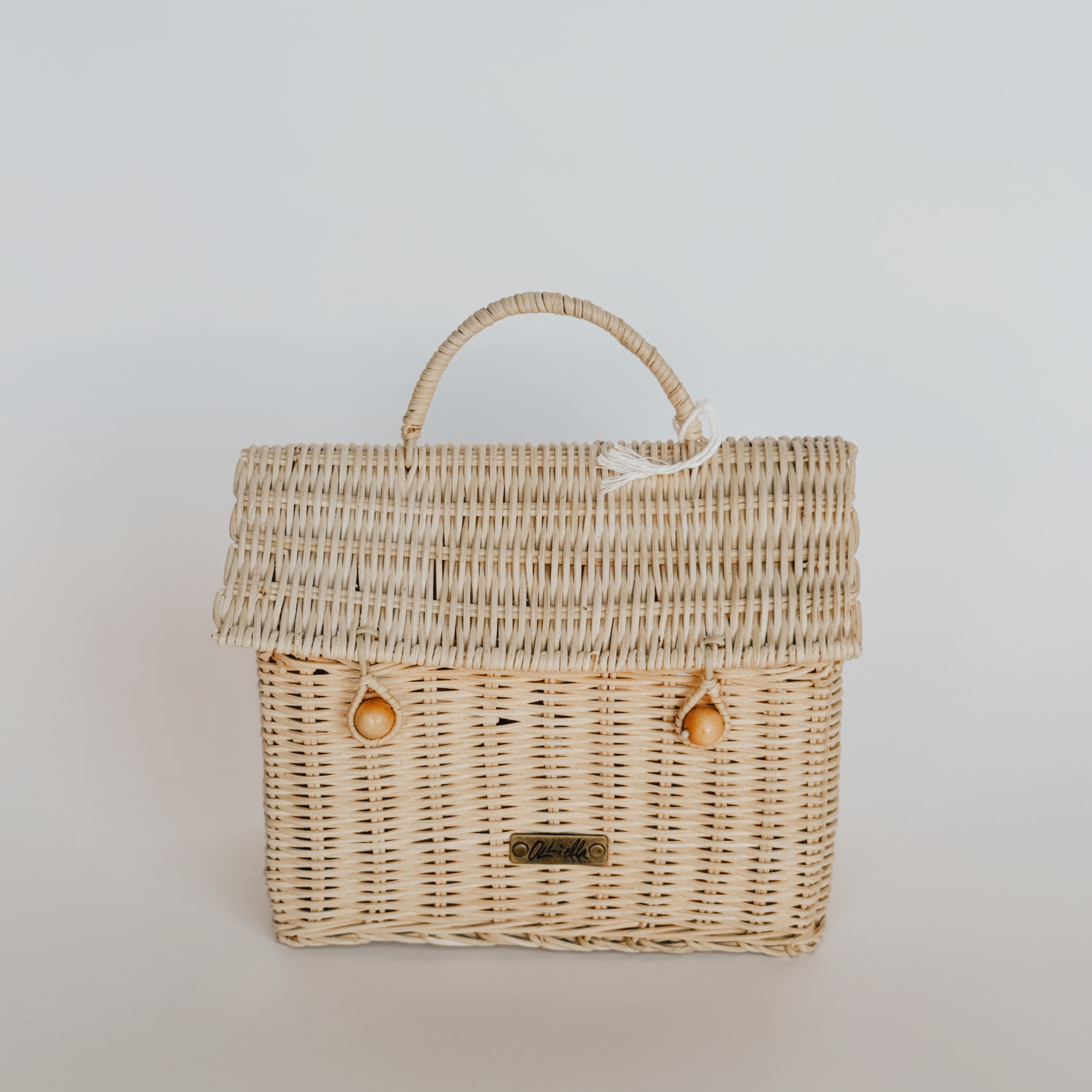 The Olli Ella - Basket House by Grace & Company is a wicker basket with handle, hinged lid, and gold label.