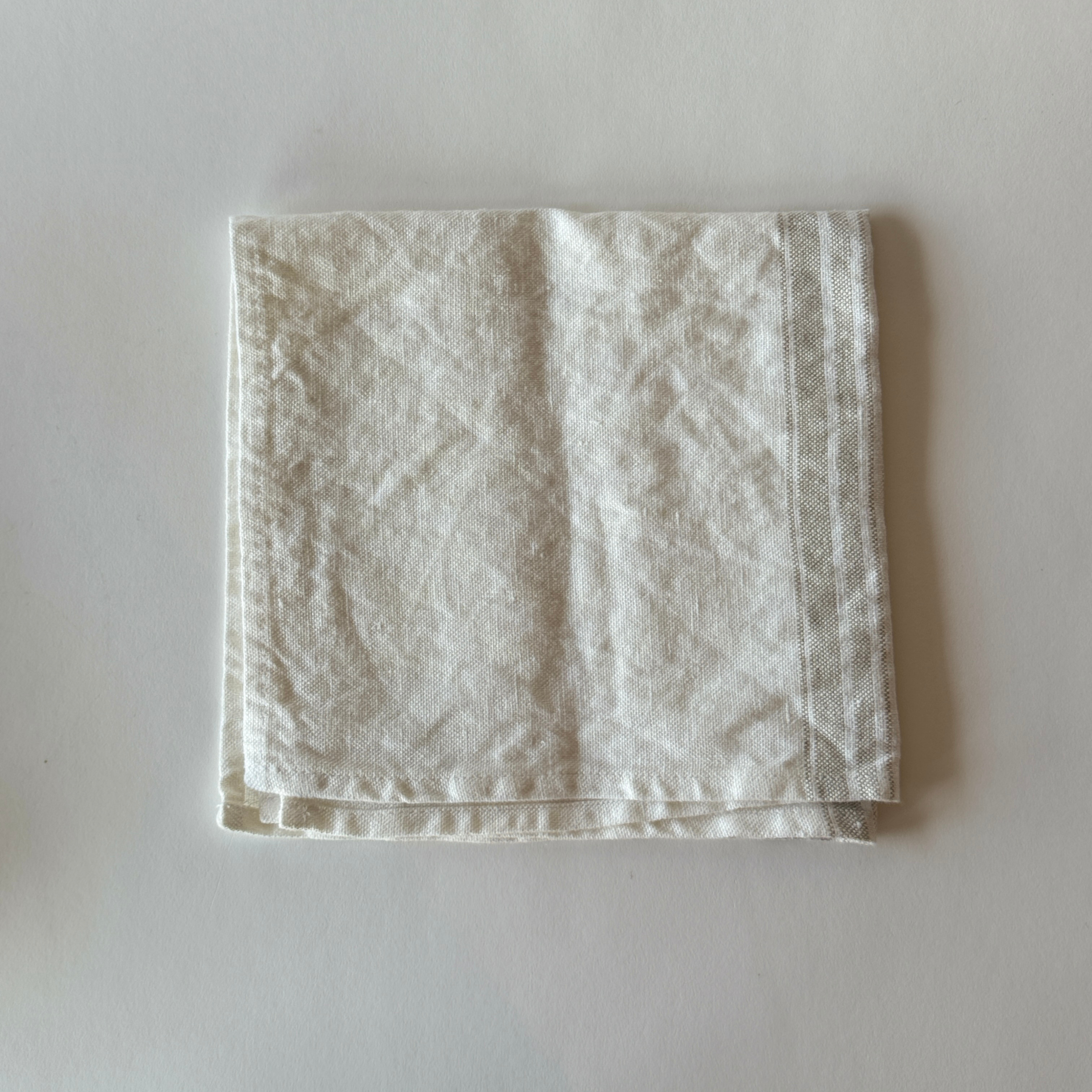 A Linen Way - Maison Table Napkin by Grace & Company, neatly folded on a light, plain surface.