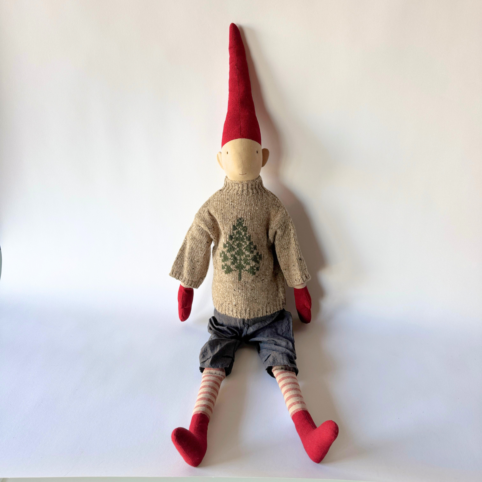 The Maileg - Christmas Pixy by Grace & Company sits against a white background in festive red and green attire.