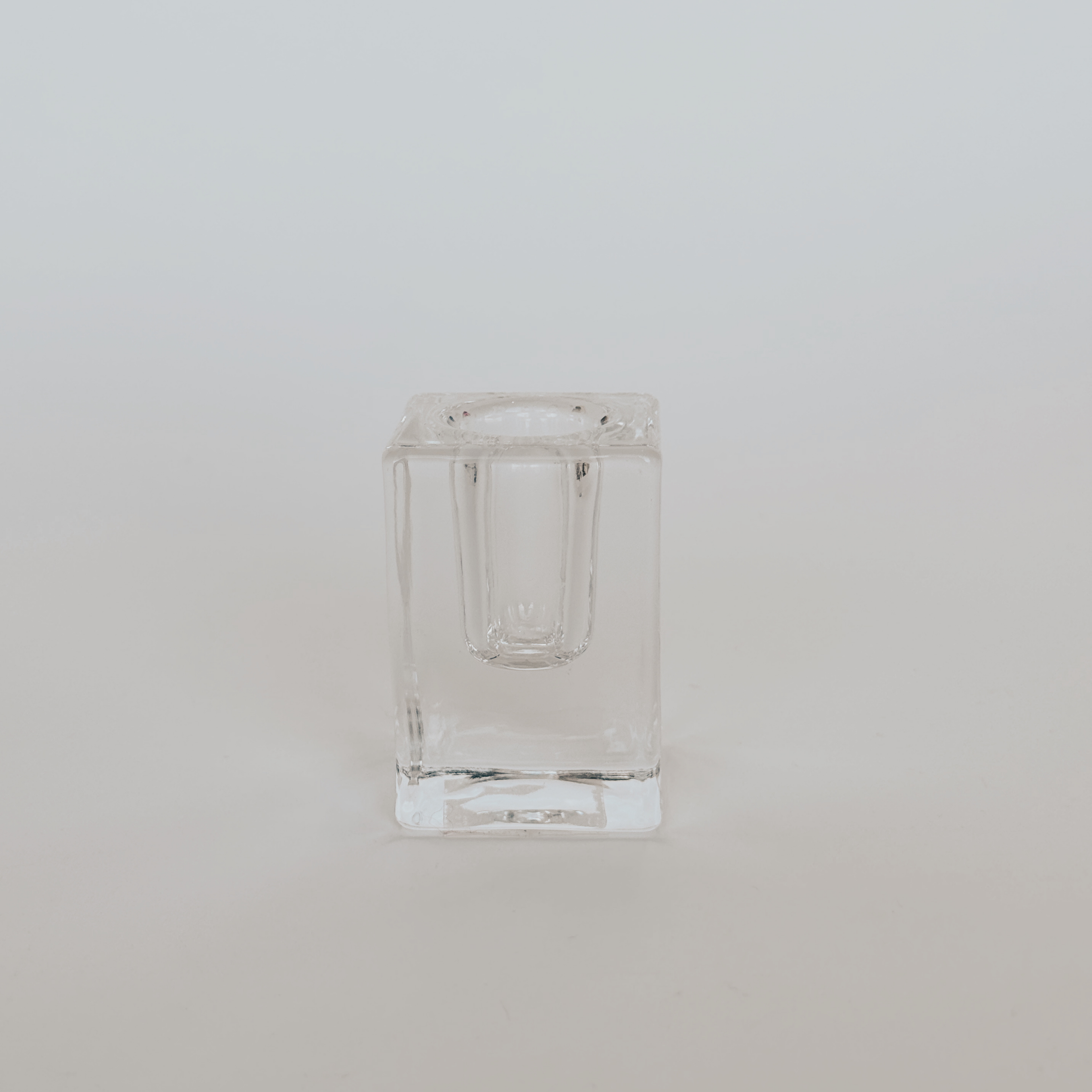A clear, square Glass Taper Candle Holder by Grace & Company is centered on a plain white background.