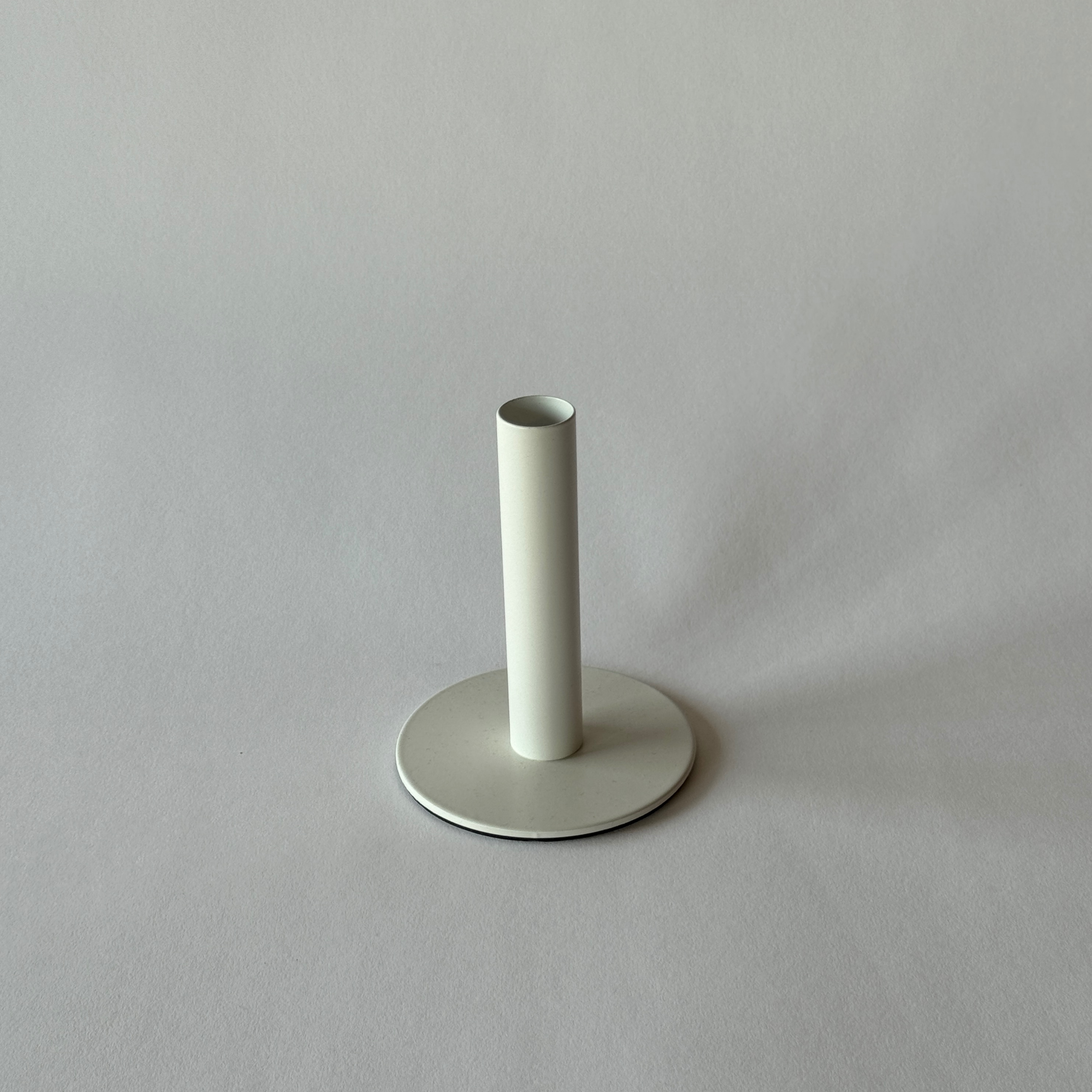 The Grace & Company Dansk Candle Holder is a minimal white cylinder with a round base on a light gray surface.