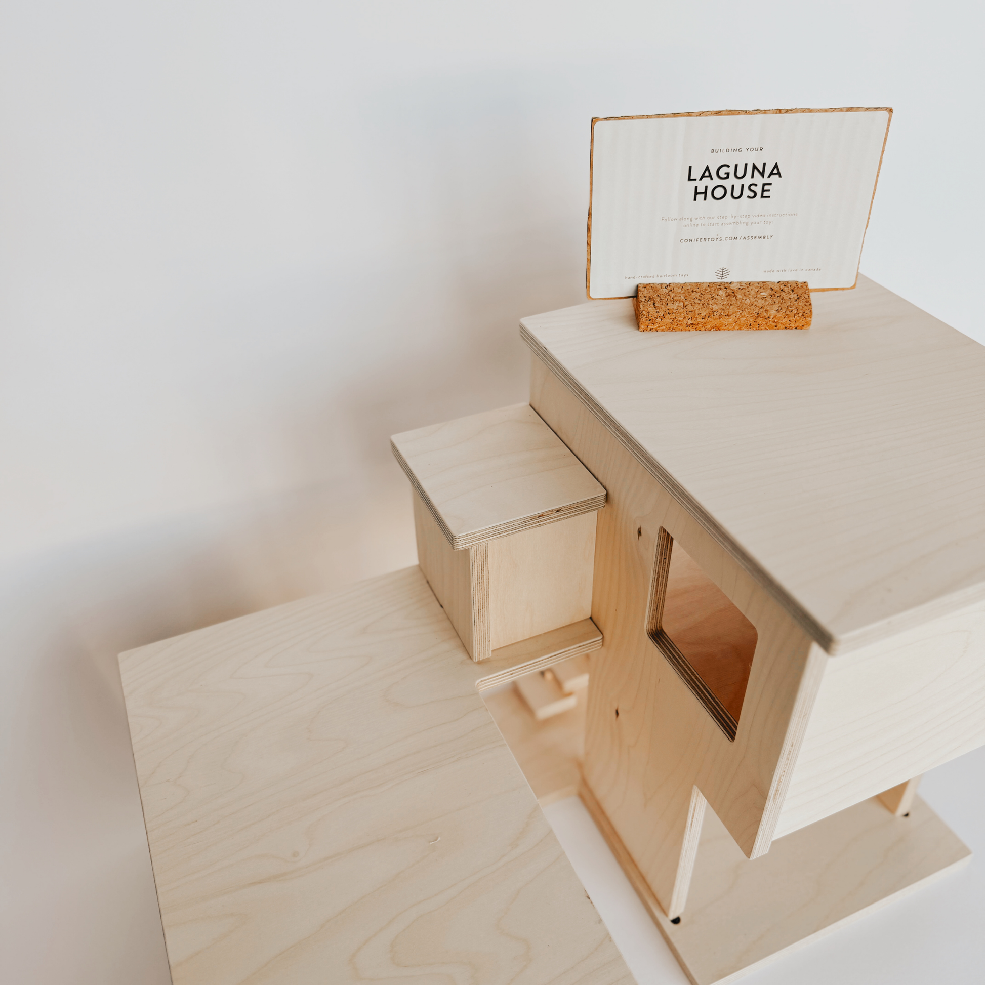 Grace & Company’s Laguna House: a wooden model with sign in cork holder, displayed on a white background.