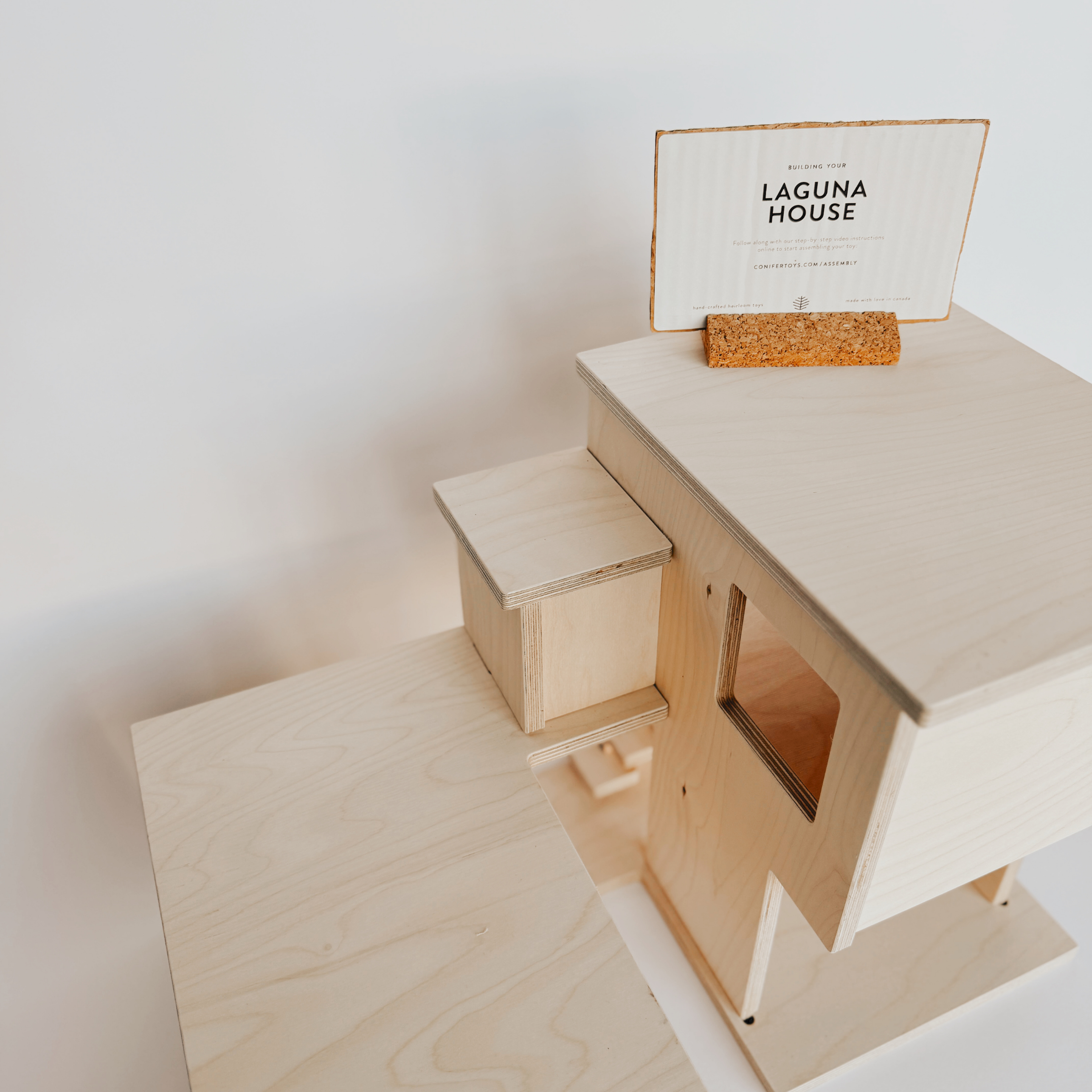Grace & Company’s Laguna House: a wooden model with sign in cork holder, displayed on a white background.