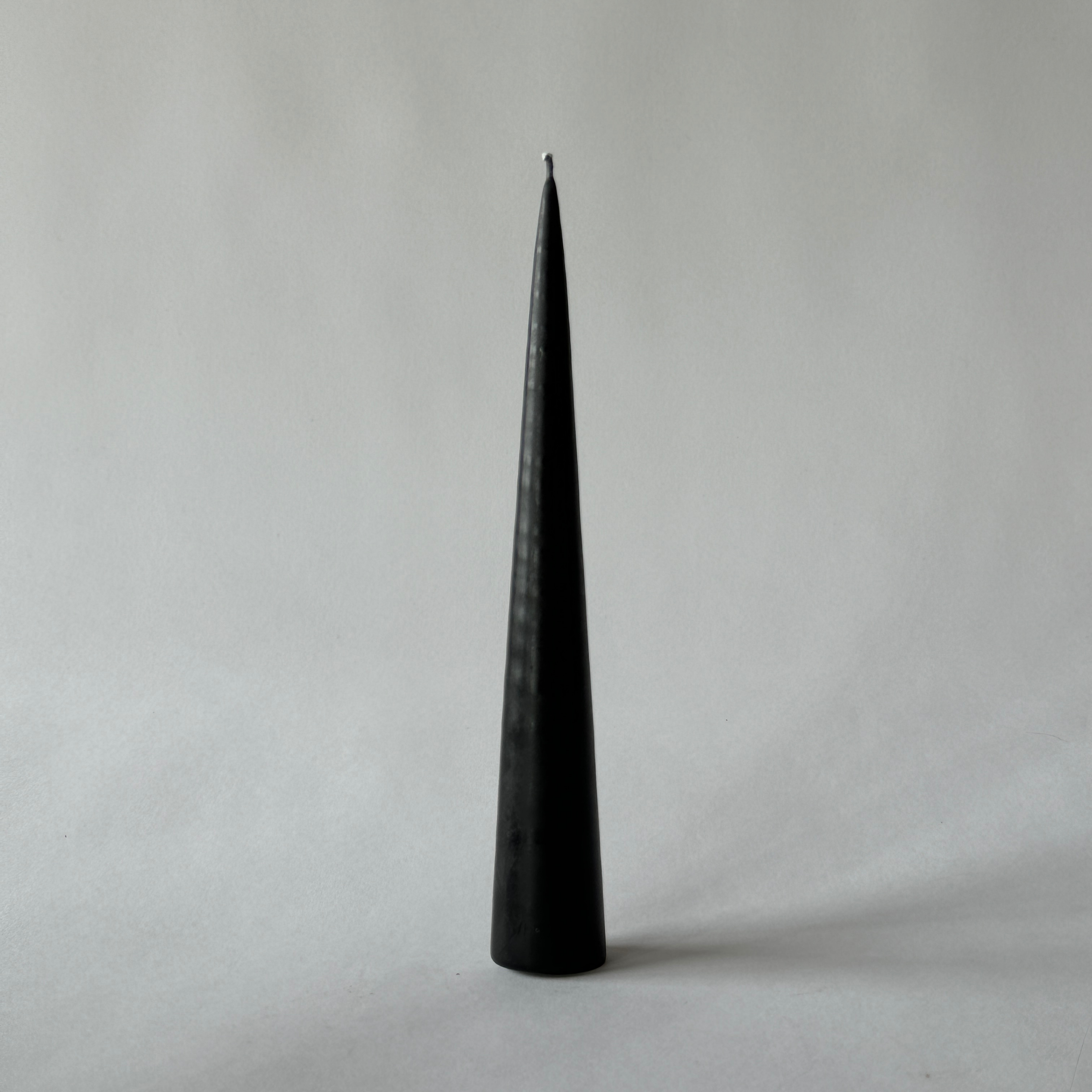 The Grace & Company Ester & Erik 10 black cone candle stands upright against a plain light gray background.