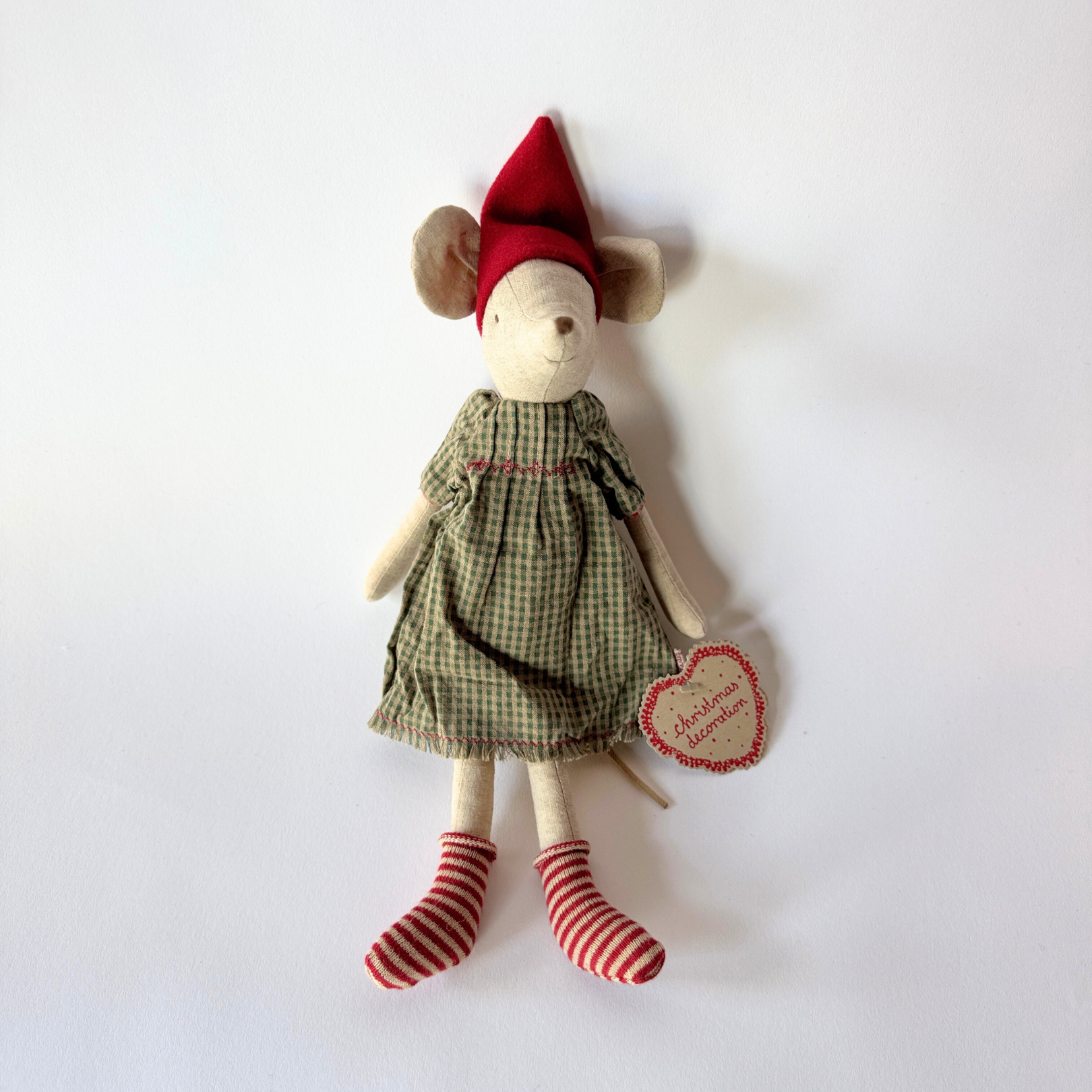 Maileg - Christmas Mouse by Grace & Company: mouse in plaid dress, red hat, striped socks, holding a heart ornament.
