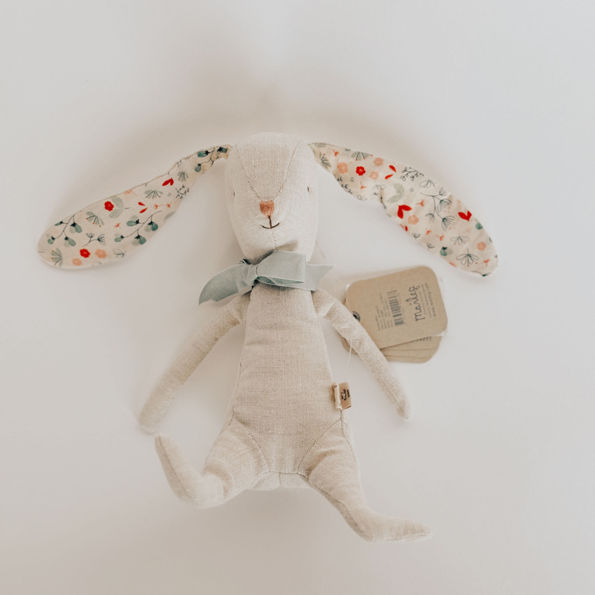 Maileg - Easter Bunny by Grace & Company: beige bunny with floral ears and blue bow on a white background.