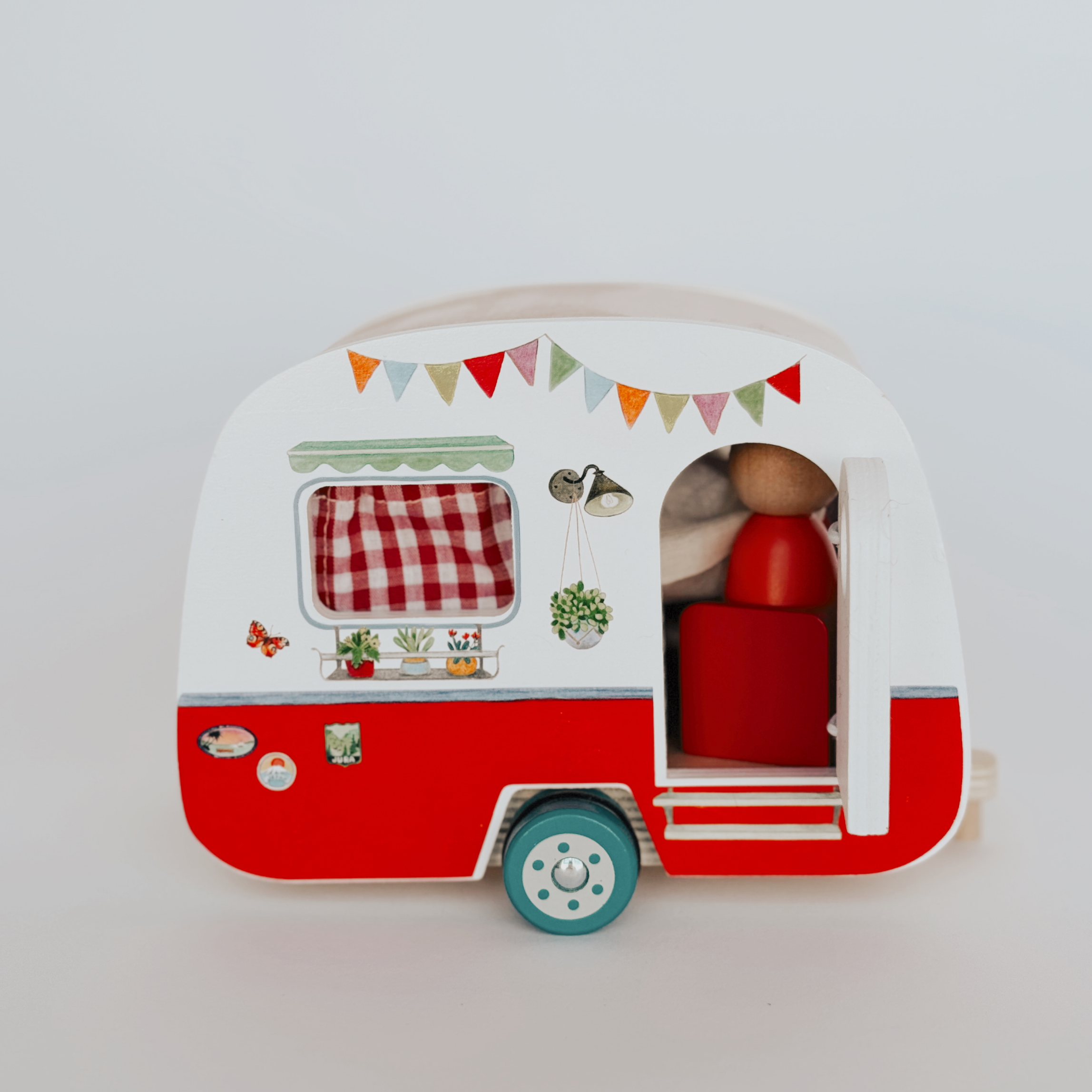 Grace & Company’s Moulin Roty Grande Famille Wood Family Set features a red and white camper with banner and wooden figure.