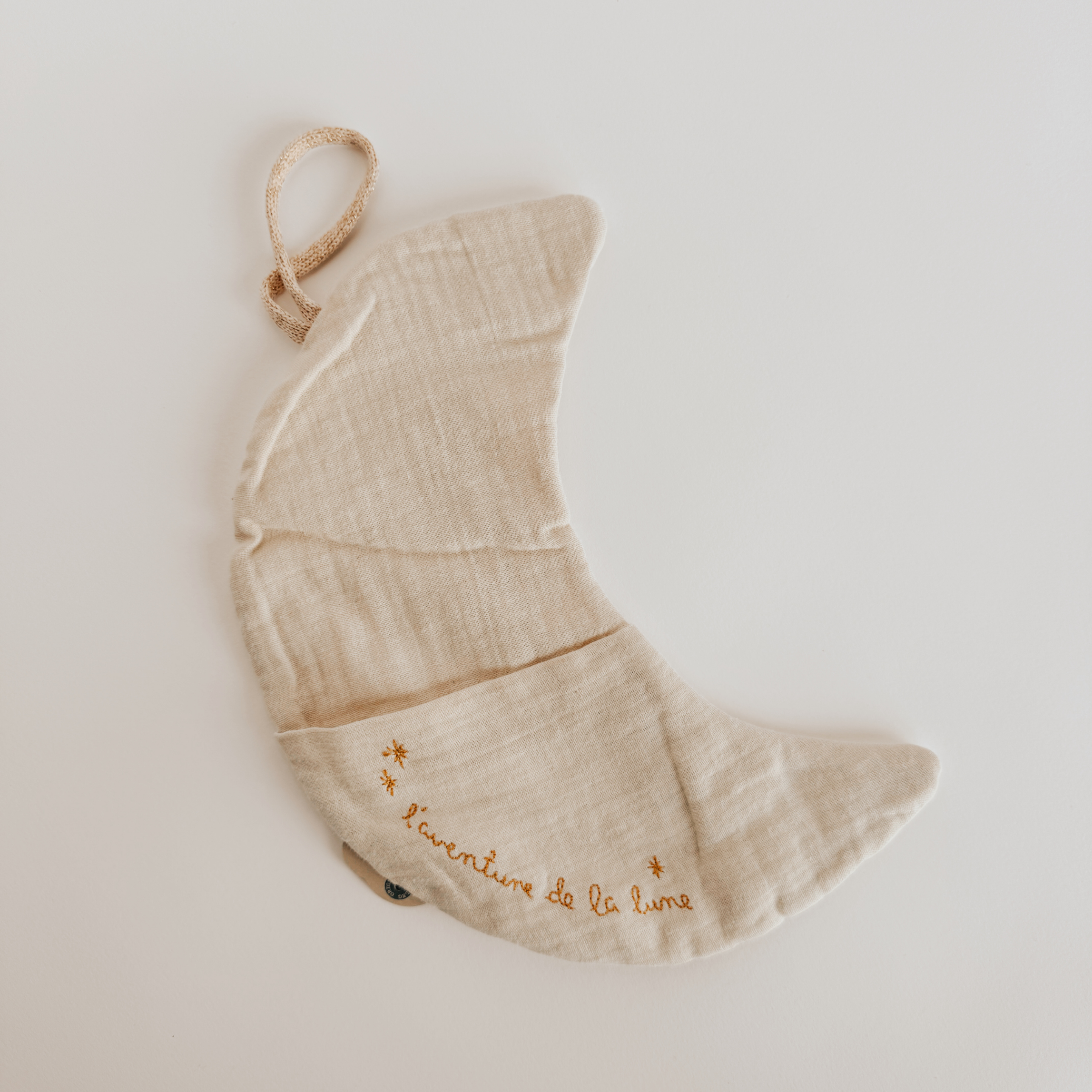 The Maileg - Laventure de la Lune by Grace & Company is a soft, beige crescent moon pillow with yellow French embroidery.