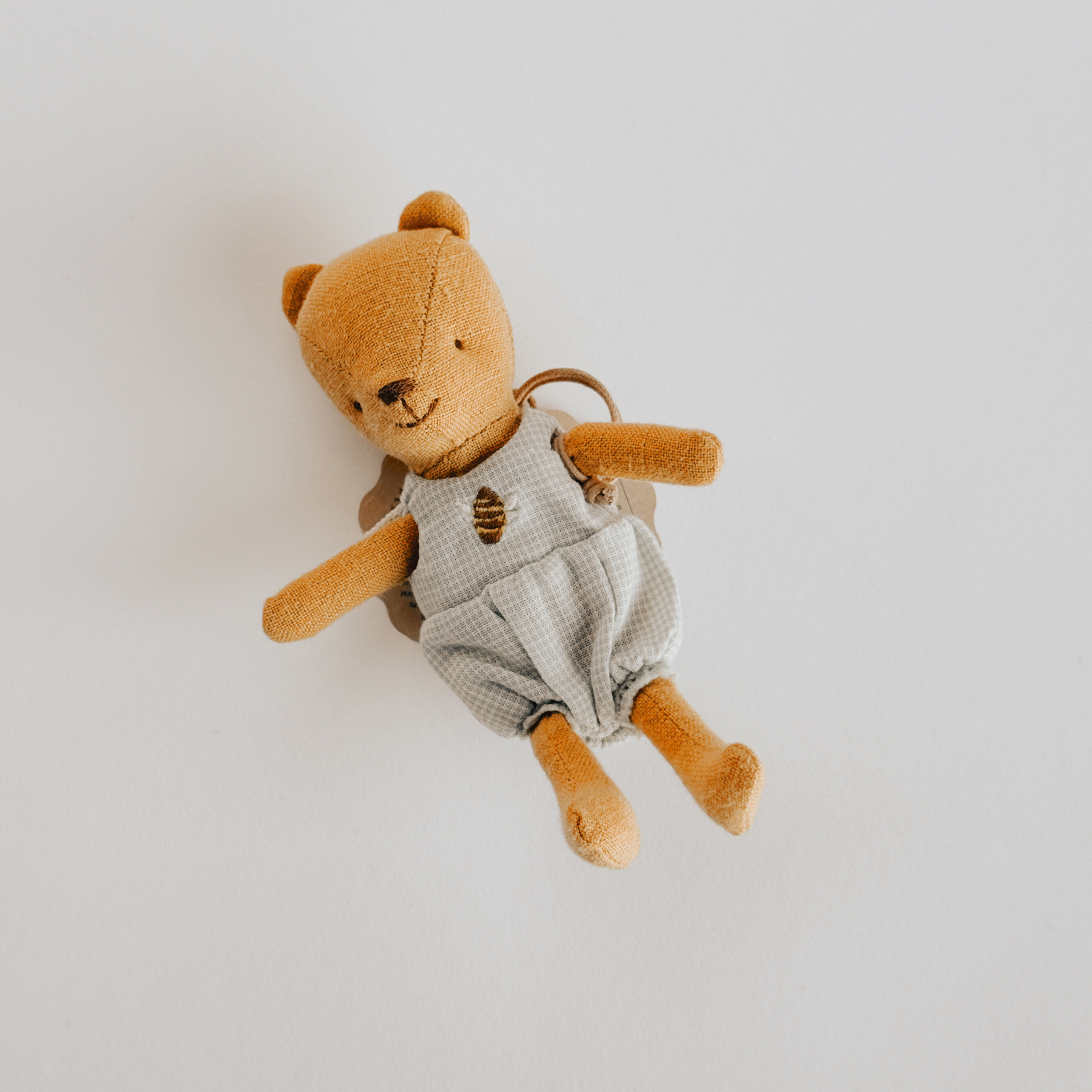 The Maileg Baby Teddy by Grace & Company is a small brown bear in gray overalls, shown on a white background.
