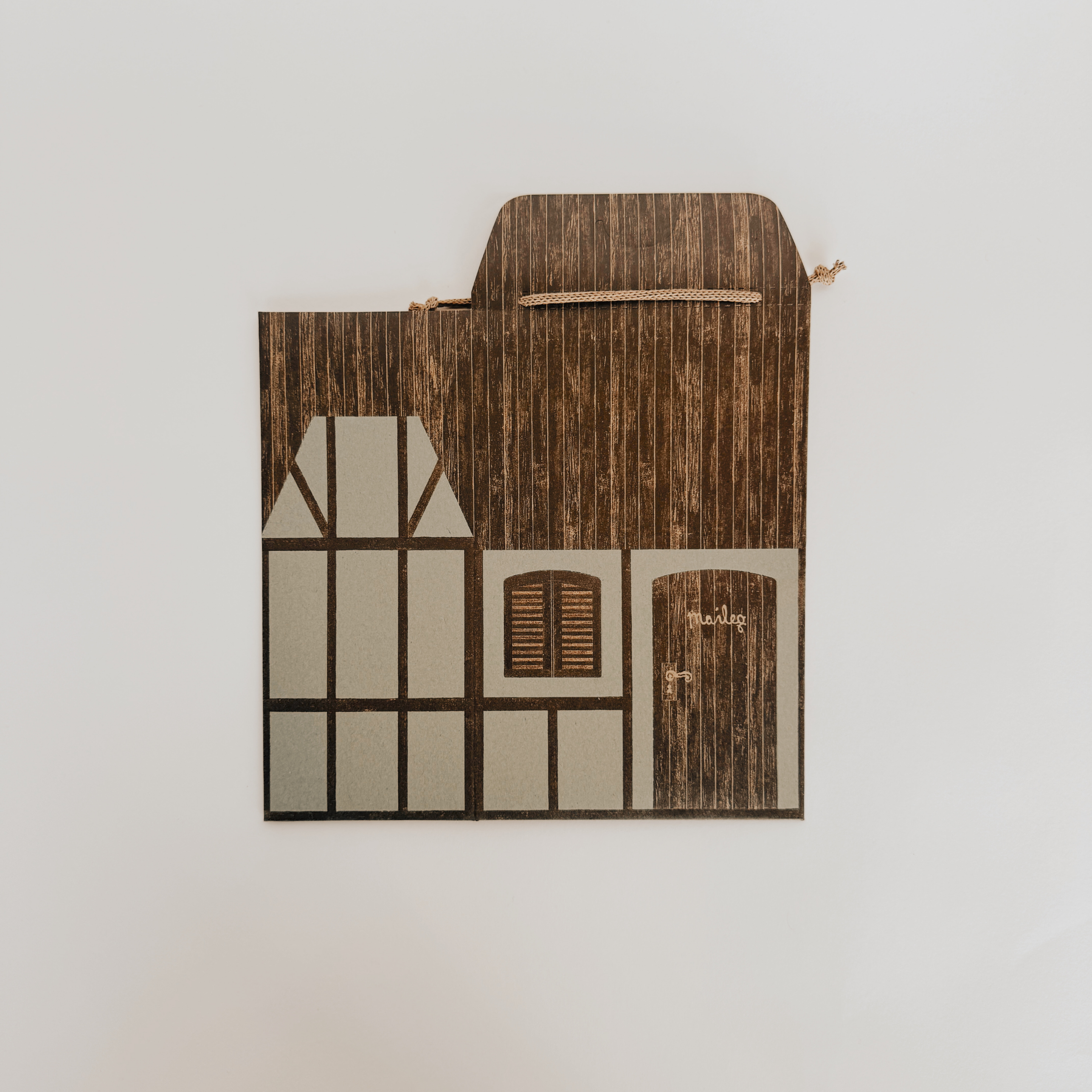 Grace & Company Maileg - Assorted Gift Wrap: flat paper model of a rustic house with timber, window, and door.