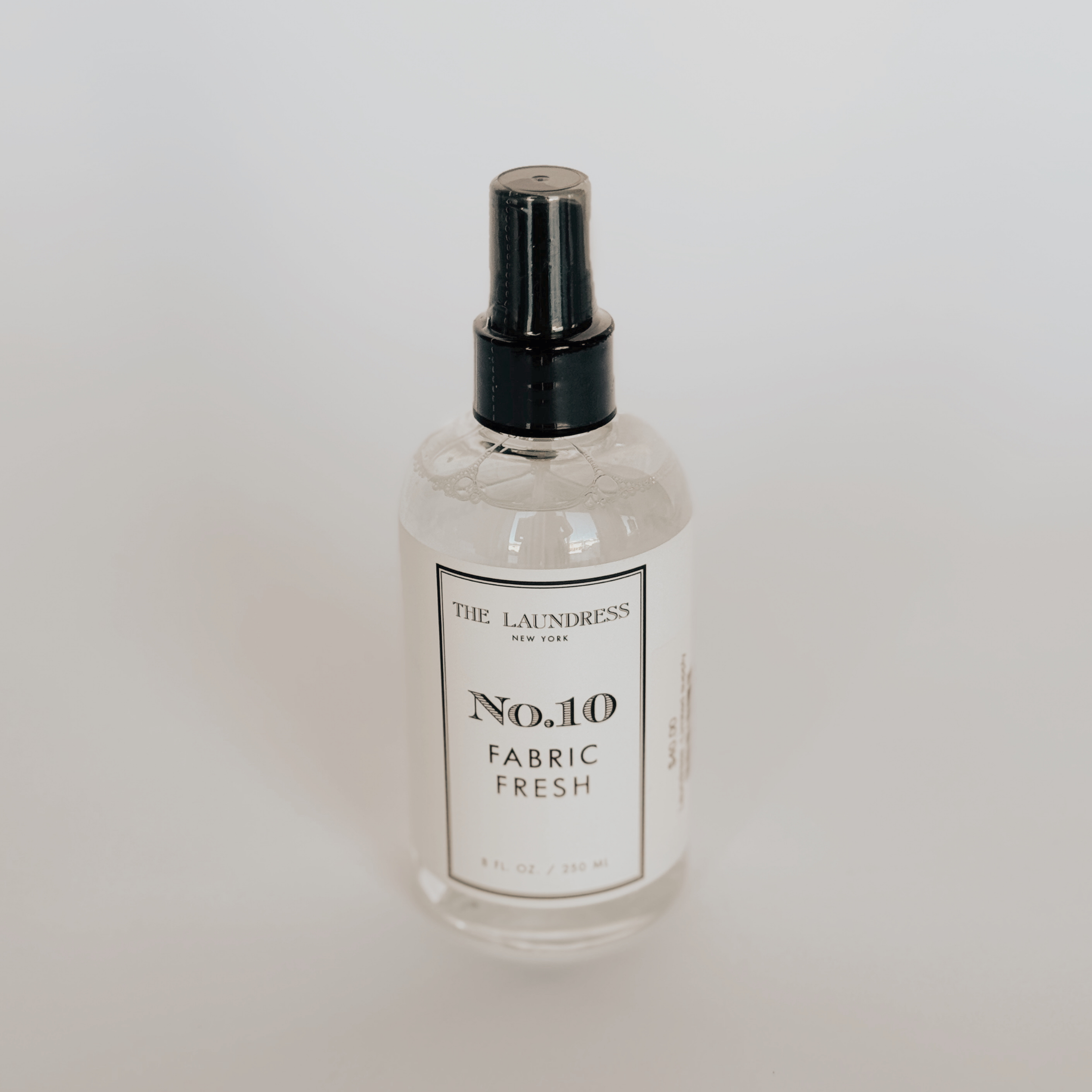 Clear spray bottle of Grace & Company Laundress - Fabric Fresh on a plain background.