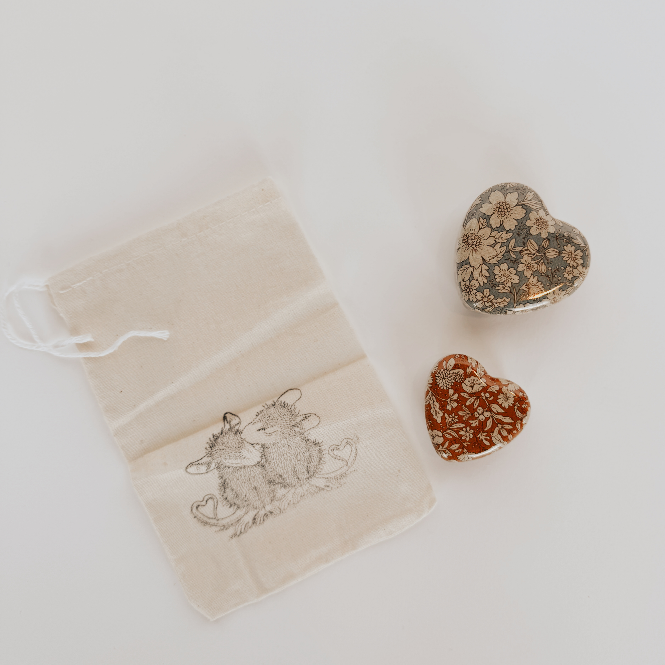 A Maileg metal heart box by Grace & Company, beside a small drawstring bag with two illustrated mice.