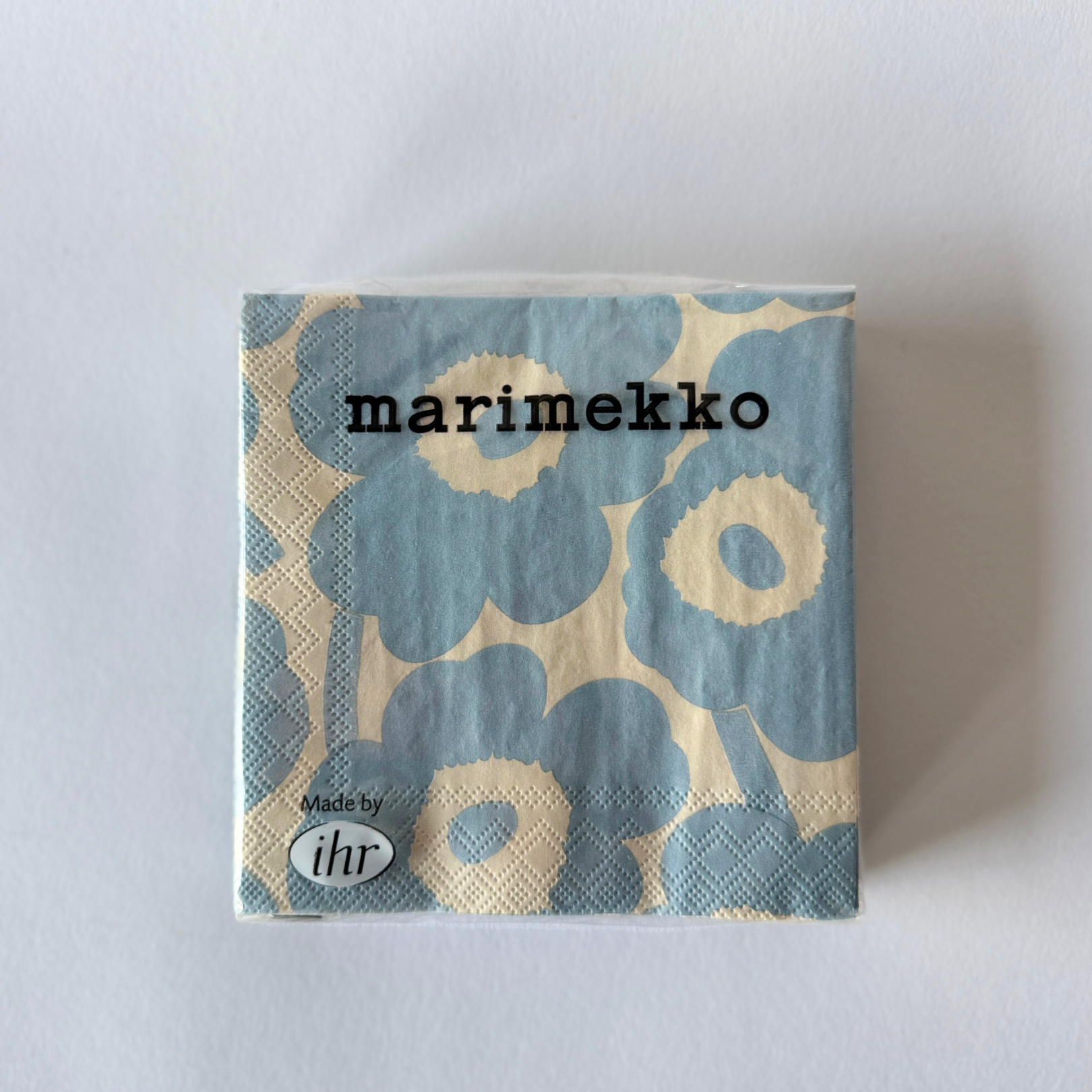Grace & Company Marimekko - Unikko Powder Blue napkin in plastic wrap, Marimekko text on front.