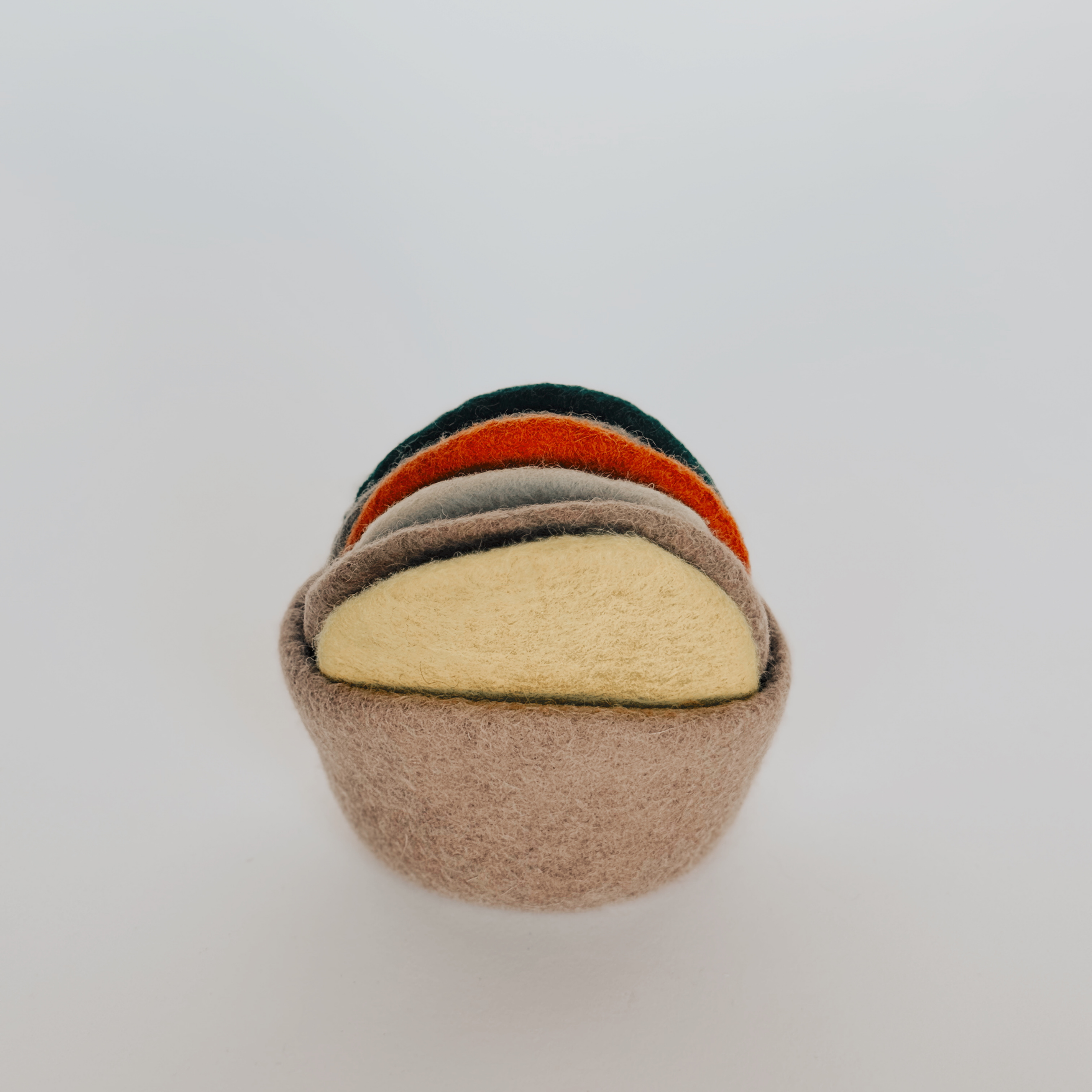 The Grace & Company Wool Coaster Set features soft, felt coasters in muted tones, arranged on a plain white background.