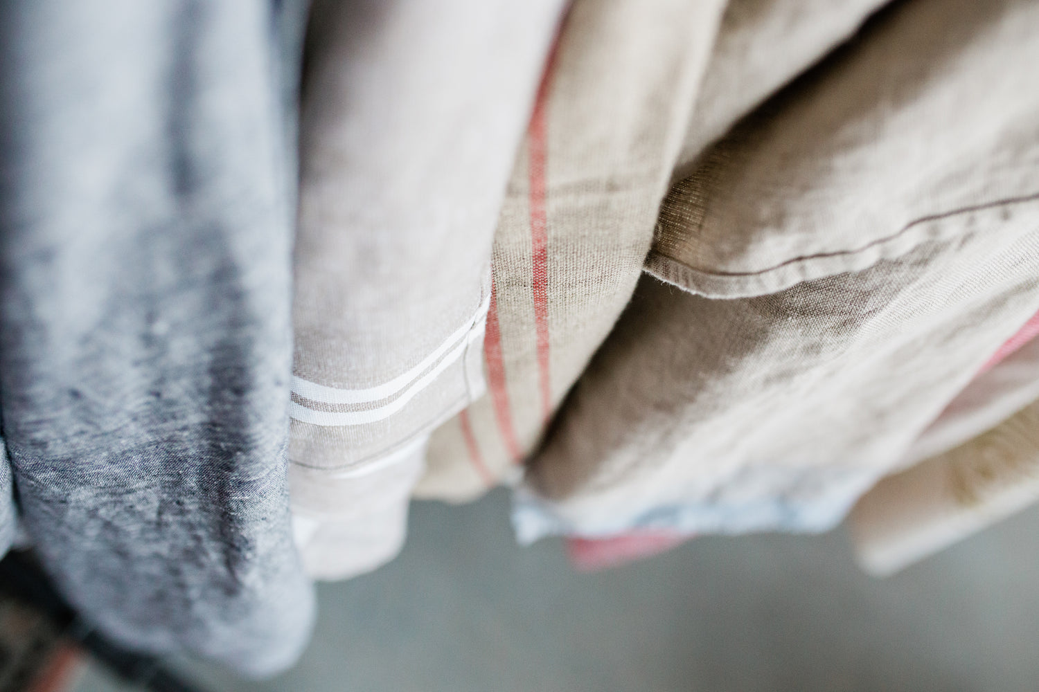 Close-up of hanging linen clothes in neutral tones with some stripes and subtle patterns.