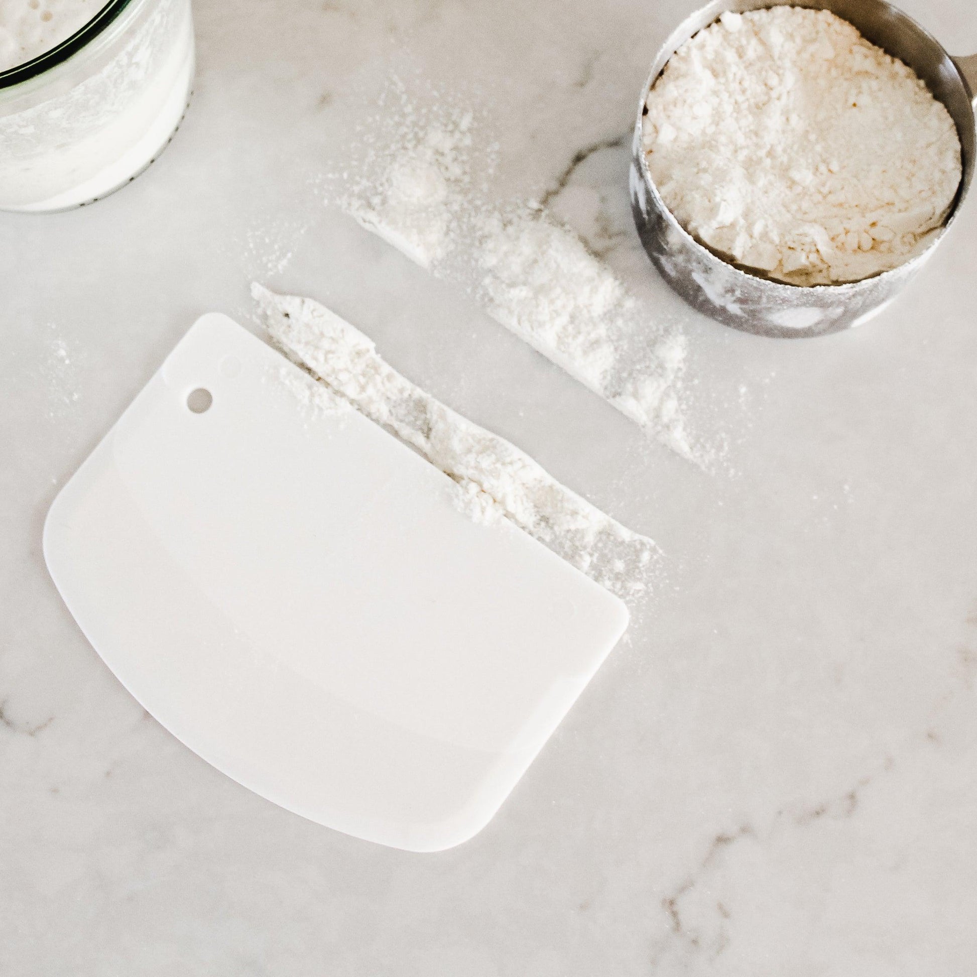 The Beneton Kids Set by Grace and Company Ltd divides flour beside a metal cup of flour on marble.