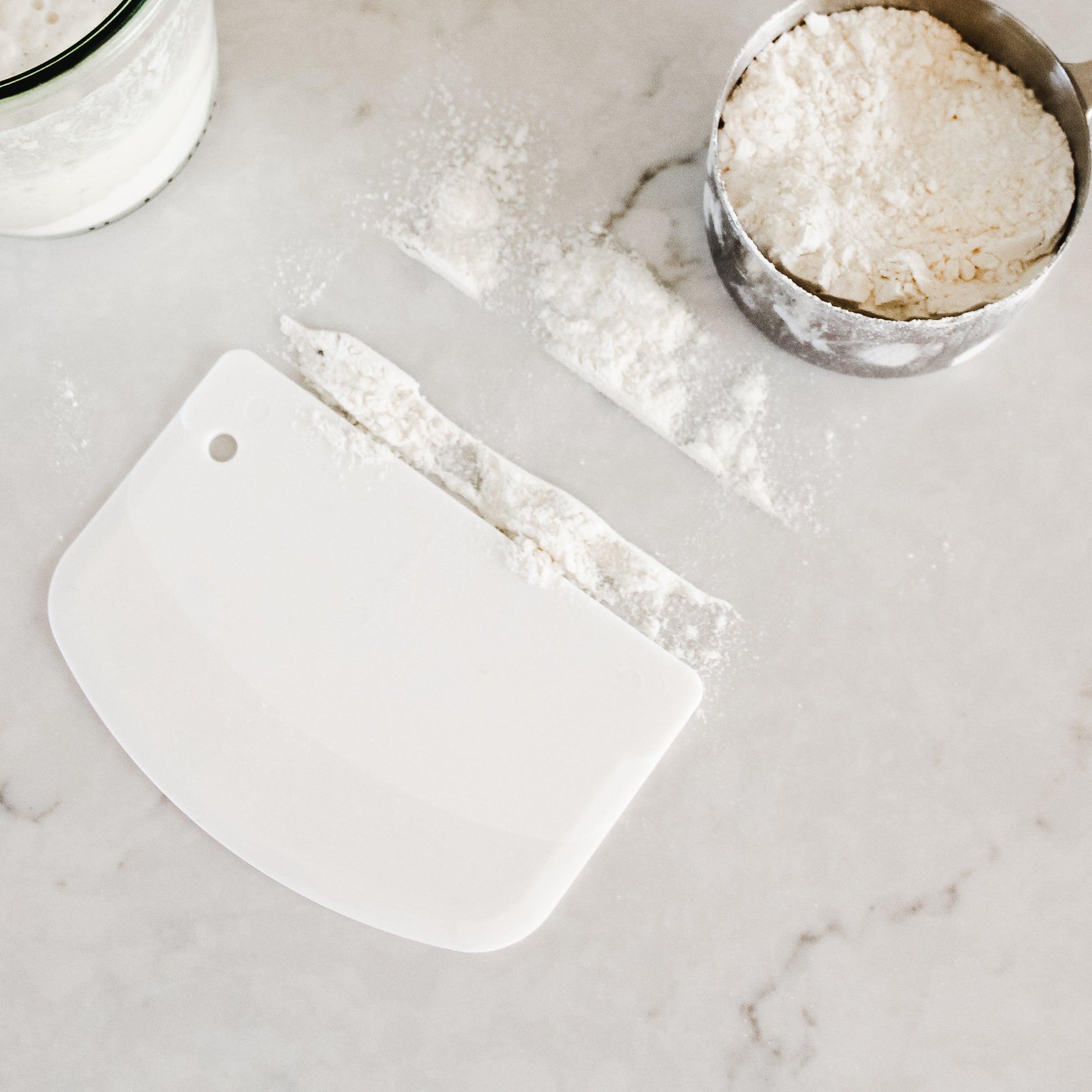 The Beneton Kids Set by Grace and Company Ltd divides flour beside a metal cup of flour on marble.