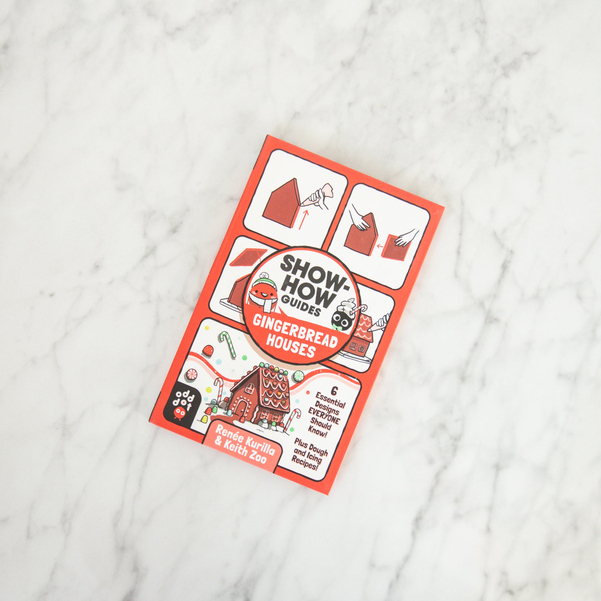 A Grace & Company Show-How Guide - Gingerbread Houses book rests on a white marble surface.