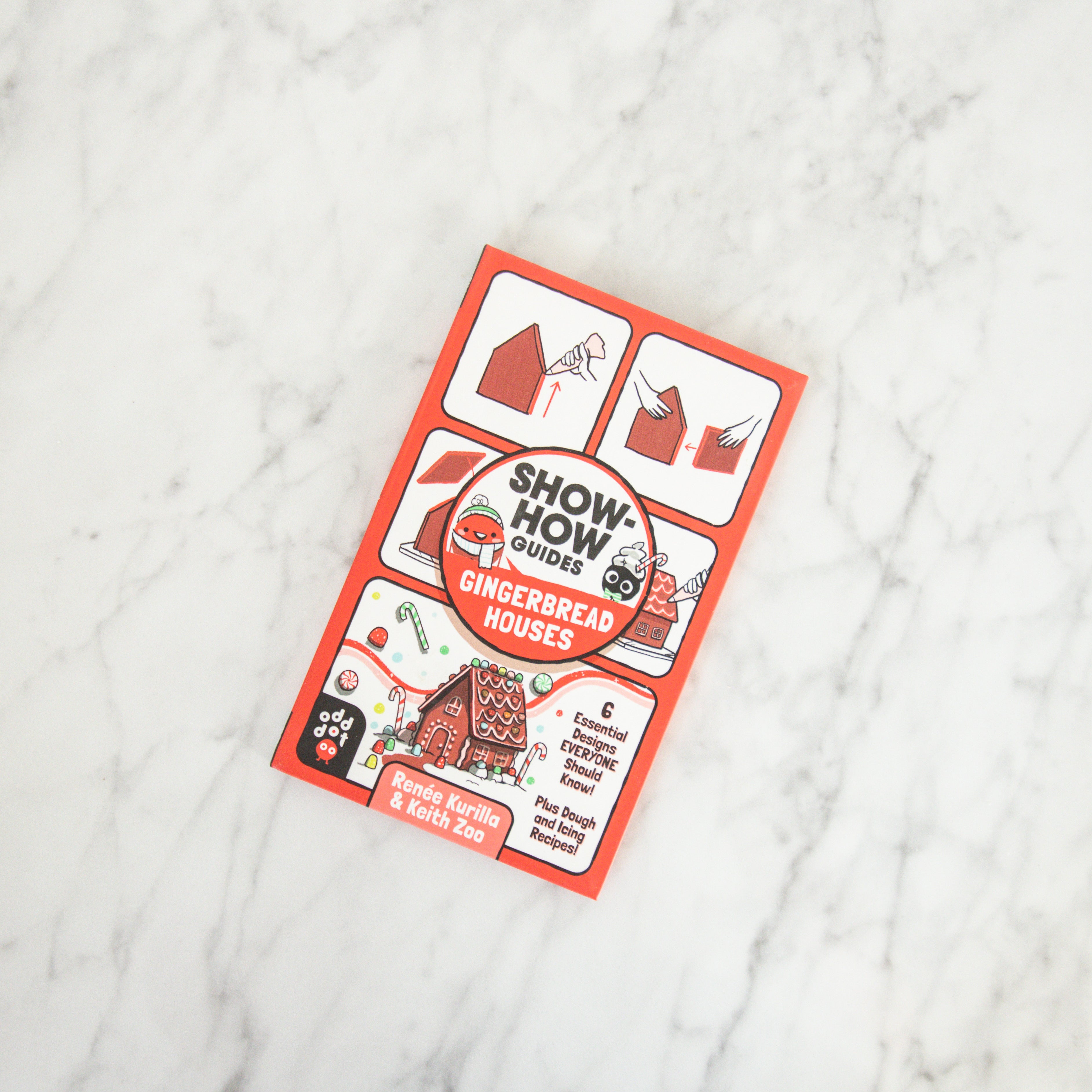 A Grace & Company Show-How Guide - Gingerbread Houses book rests on a white marble surface.