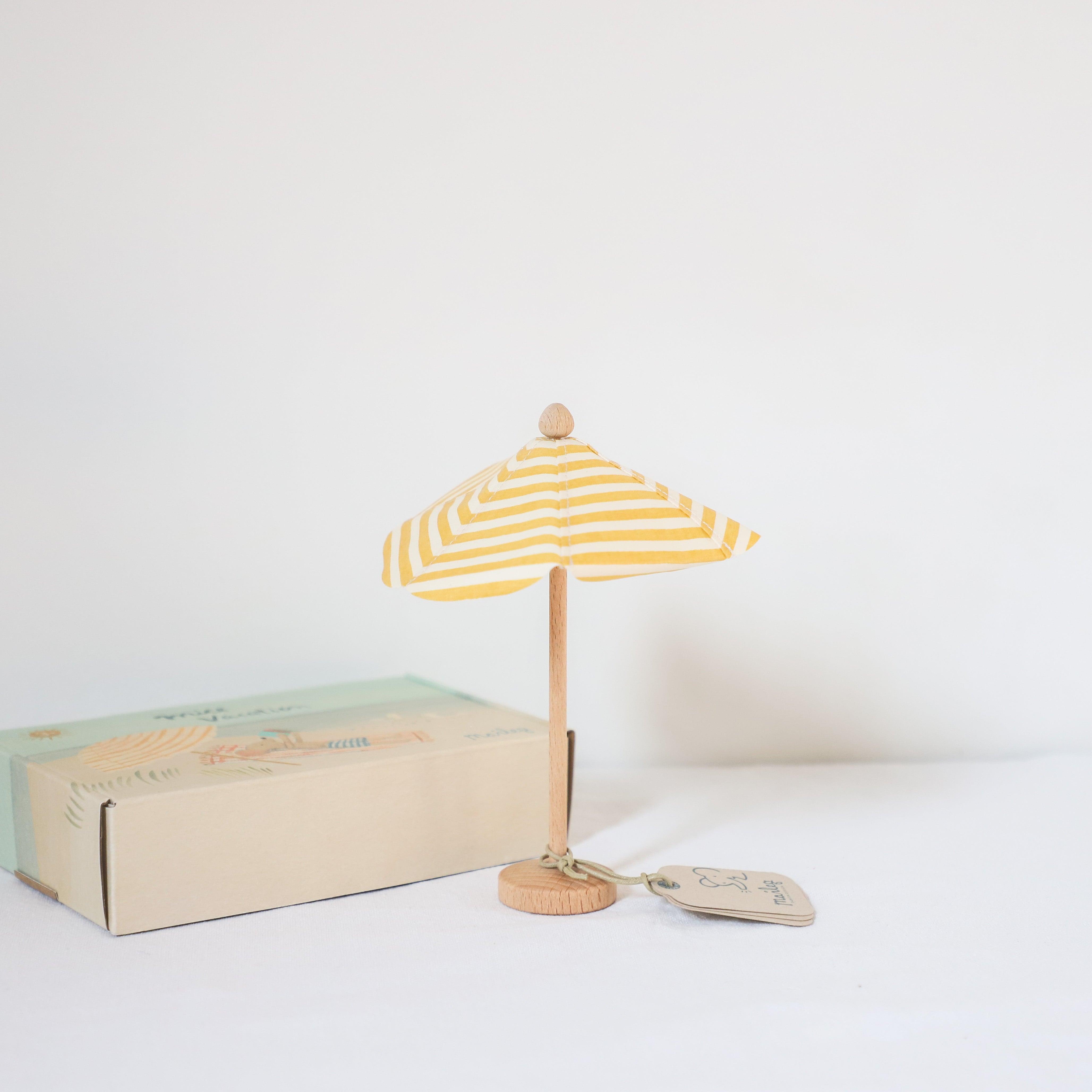 The Maileg de Plage Summer Fun by Grace and Company Ltd features a small yellow-and-white striped toy beach umbrella.