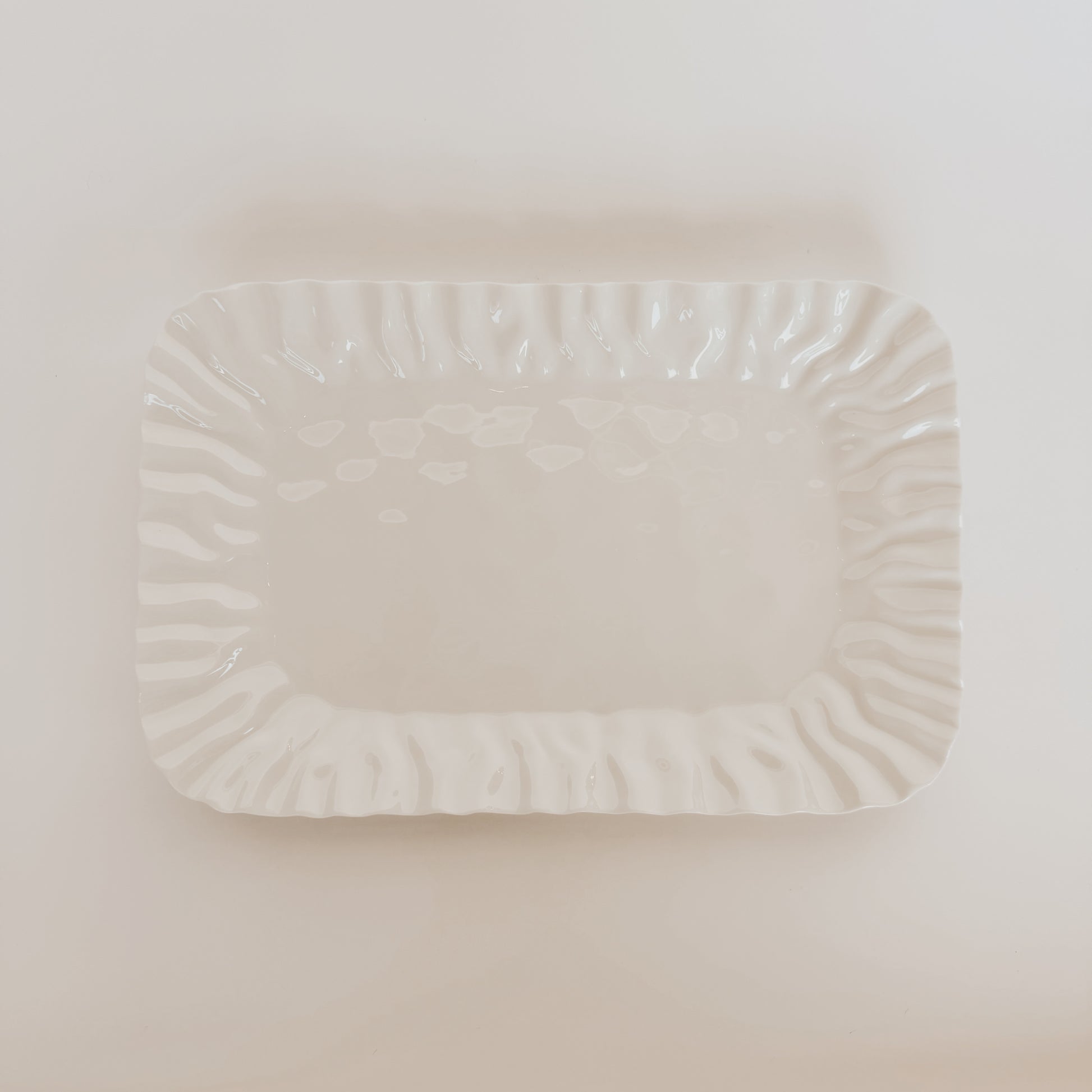 Mascali Bianca Serve Collection by Grace and Company Ltd: rectangular white ceramic plate with a wavy, textured edge.