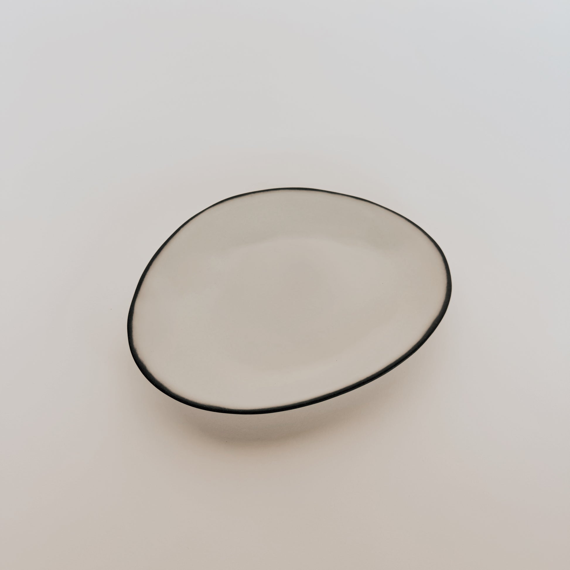 A simple, round Stacked Organic - Appetizer Plate - Salt by Grace and Company Ltd on a plain light background.