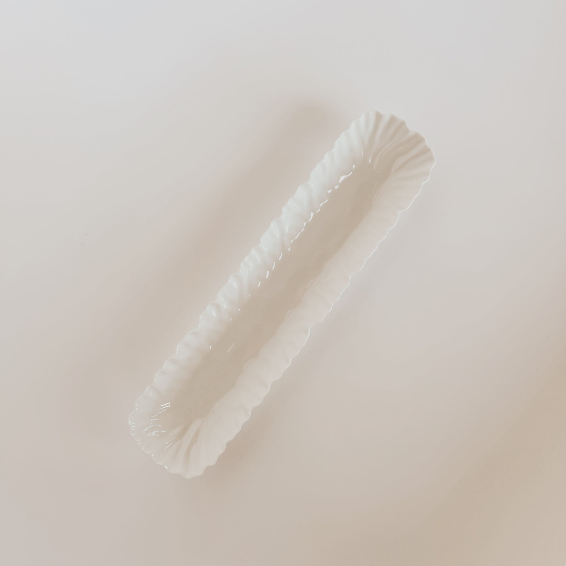 The Mascali Bianca Serve Collection dish by Grace and Company Ltd features a long, white, scalloped-edge design.
