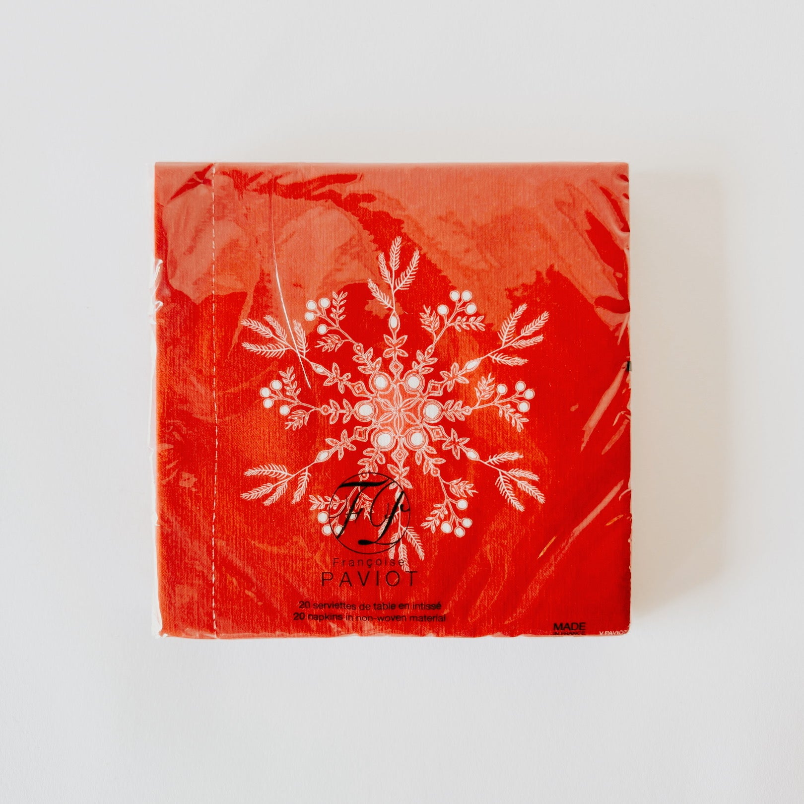 Grace & Company Paviot Dinner Napkins, red with white snowflake design, packaged on a plain white background.