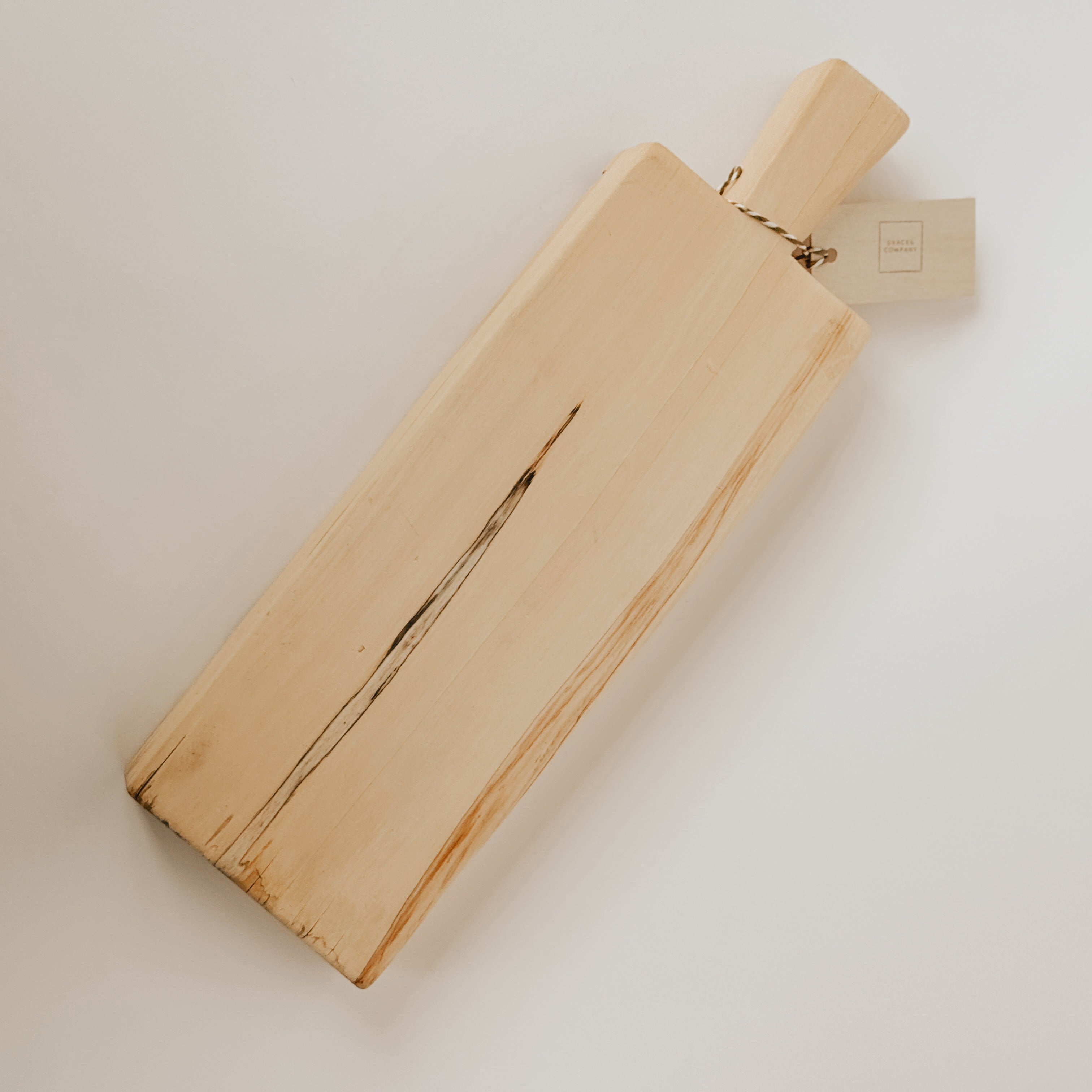 The Grace & Company Custom Birch Board features a handle and natural center crack, shown on a light surface.