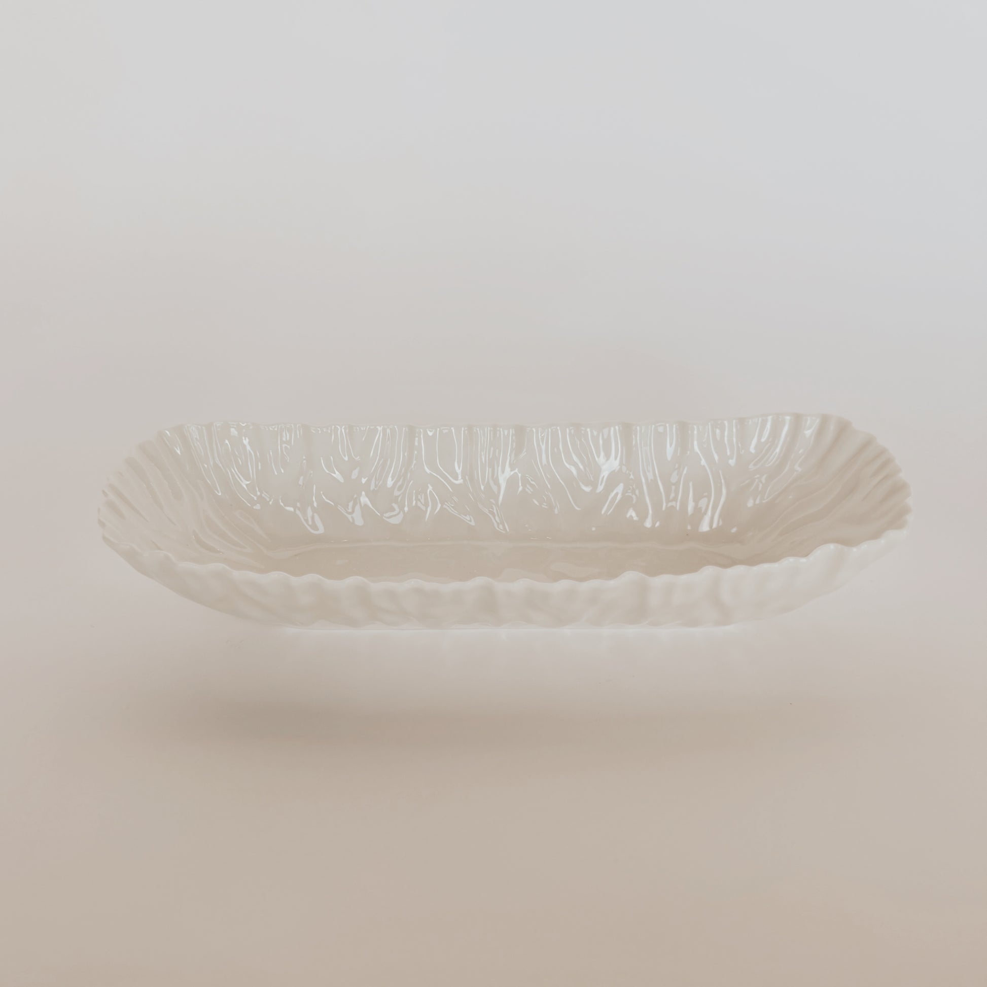 The Mascali Bianca Serve Collection by Grace and Company Ltd features a white rectangular ceramic dish with a wavy rim.