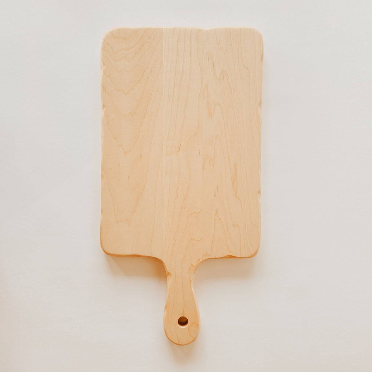 The Grace & Company Biglow Woodcraft Charcuterie Board features a handle and hole on a plain wood design.