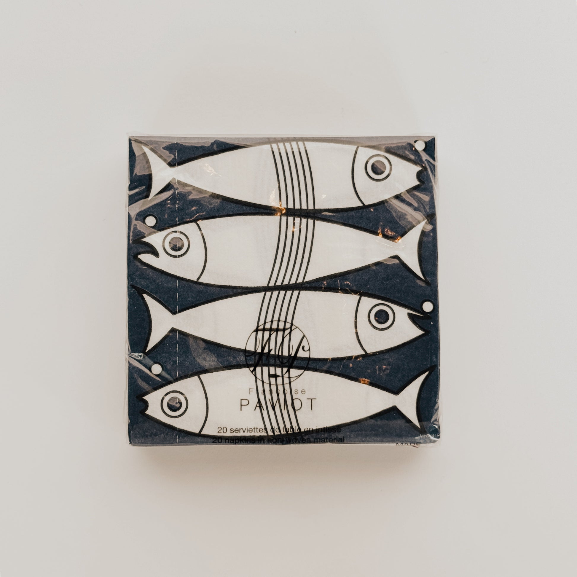Grace & Company Paviot - Fish Napkins feature a minimalist design of four white fish on a dark background.