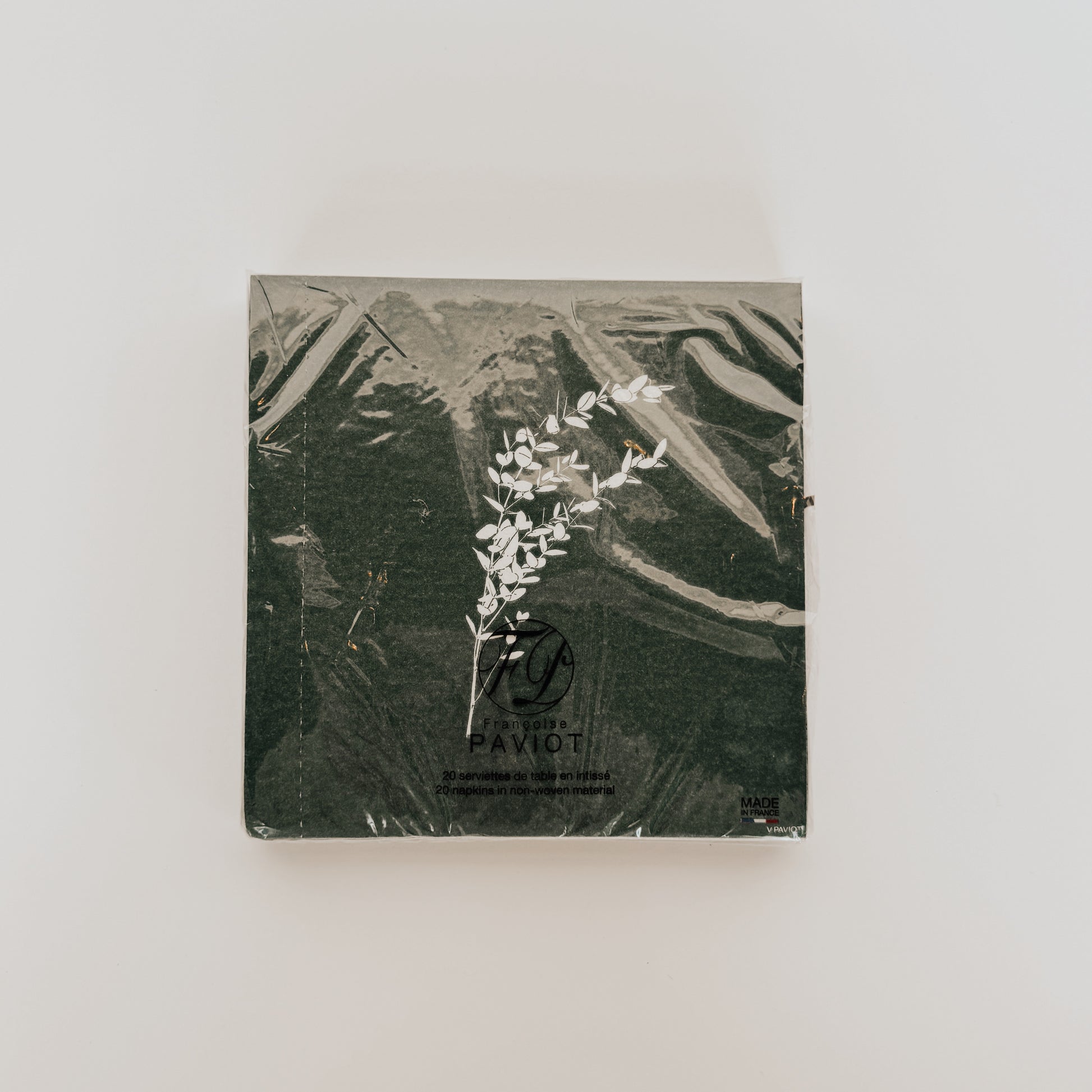 Grace & Company Paviot Dinner Napkins, green with white floral design, wrapped in plastic on a white background.