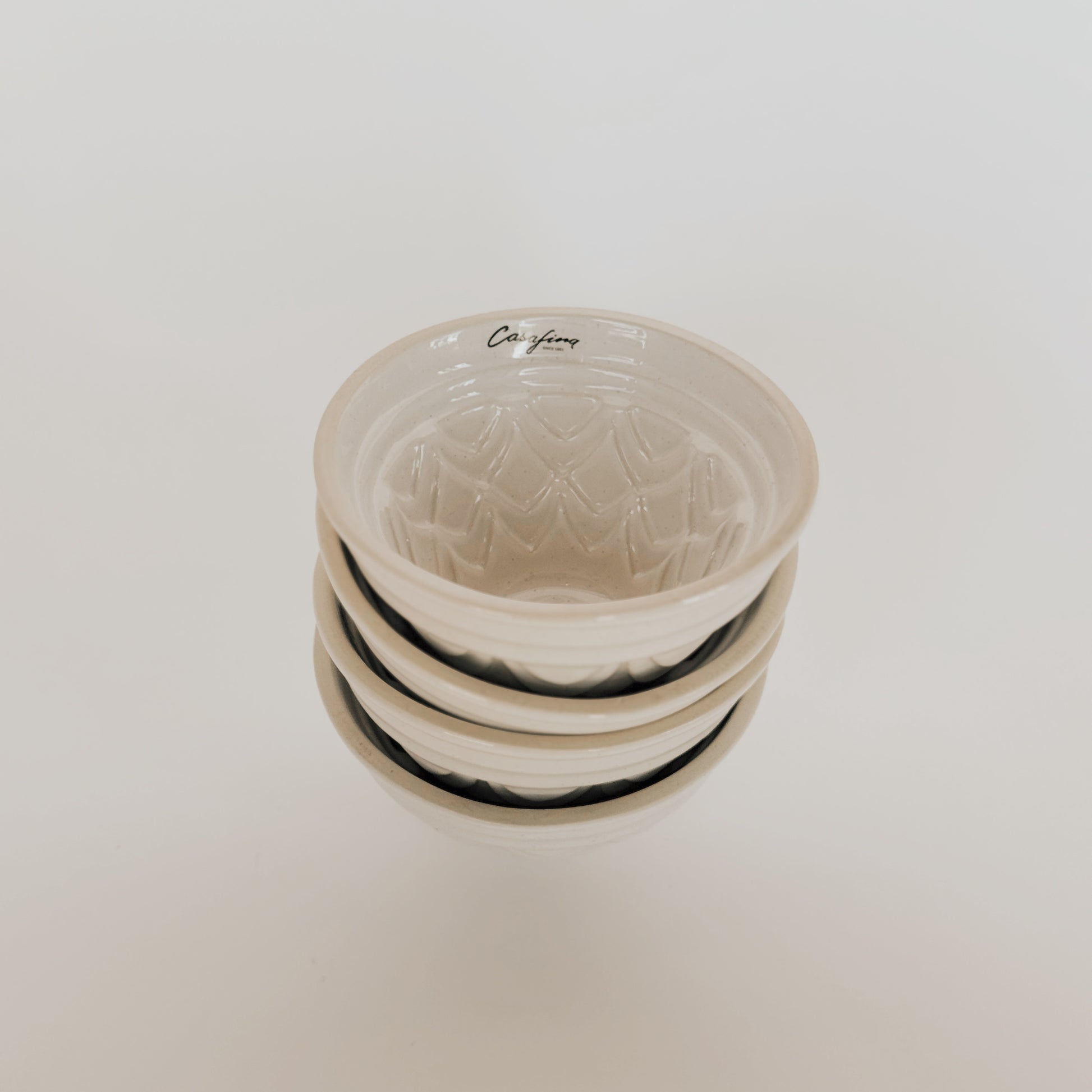 Three stacked Casafina Fatoria cake pans by Grace & Company, with subtle patterns and California inside the top pan.