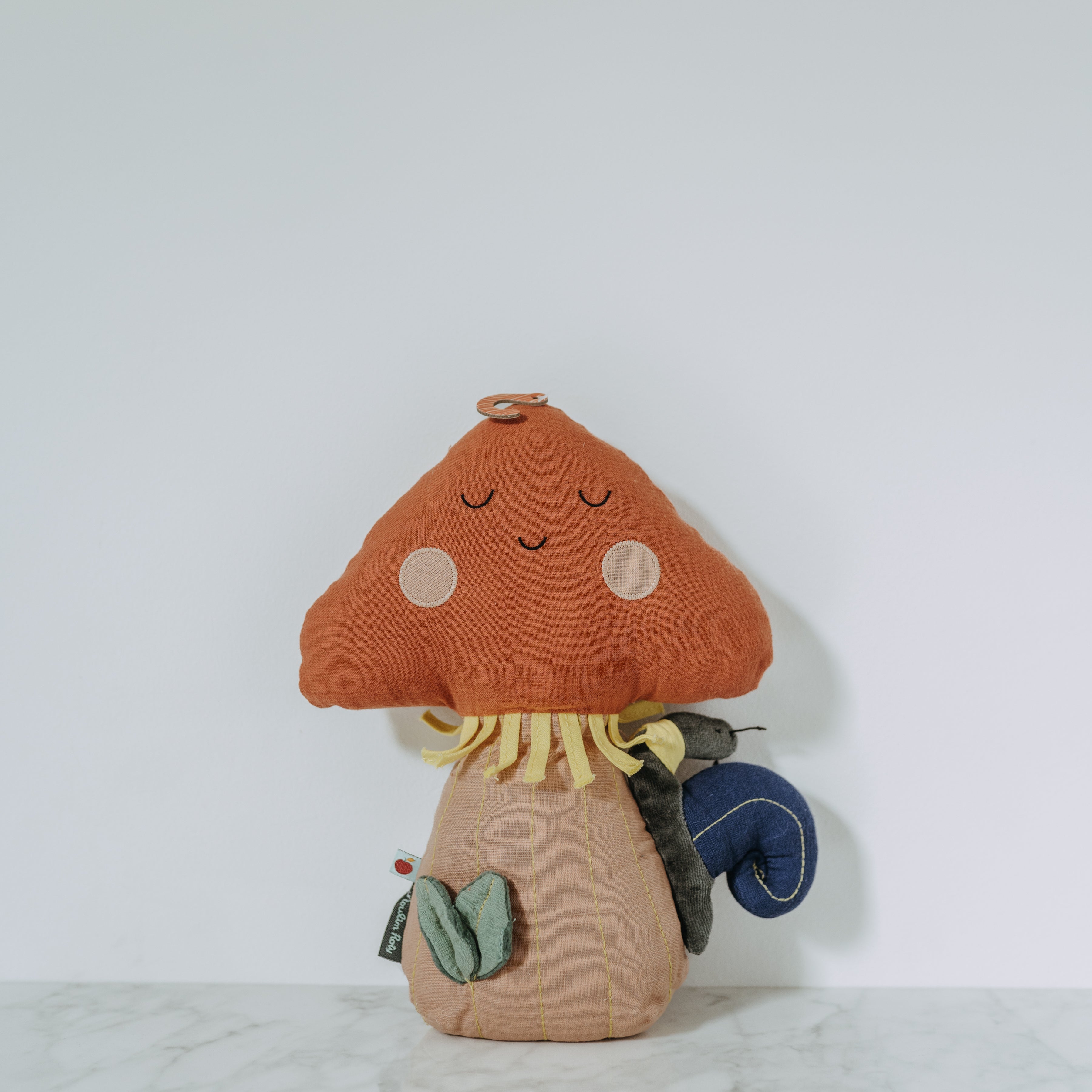 The Moulin Roty - Pomme des Bois plush by Grace and Company Ltd is a smiling mushroom toy with colorful accents.