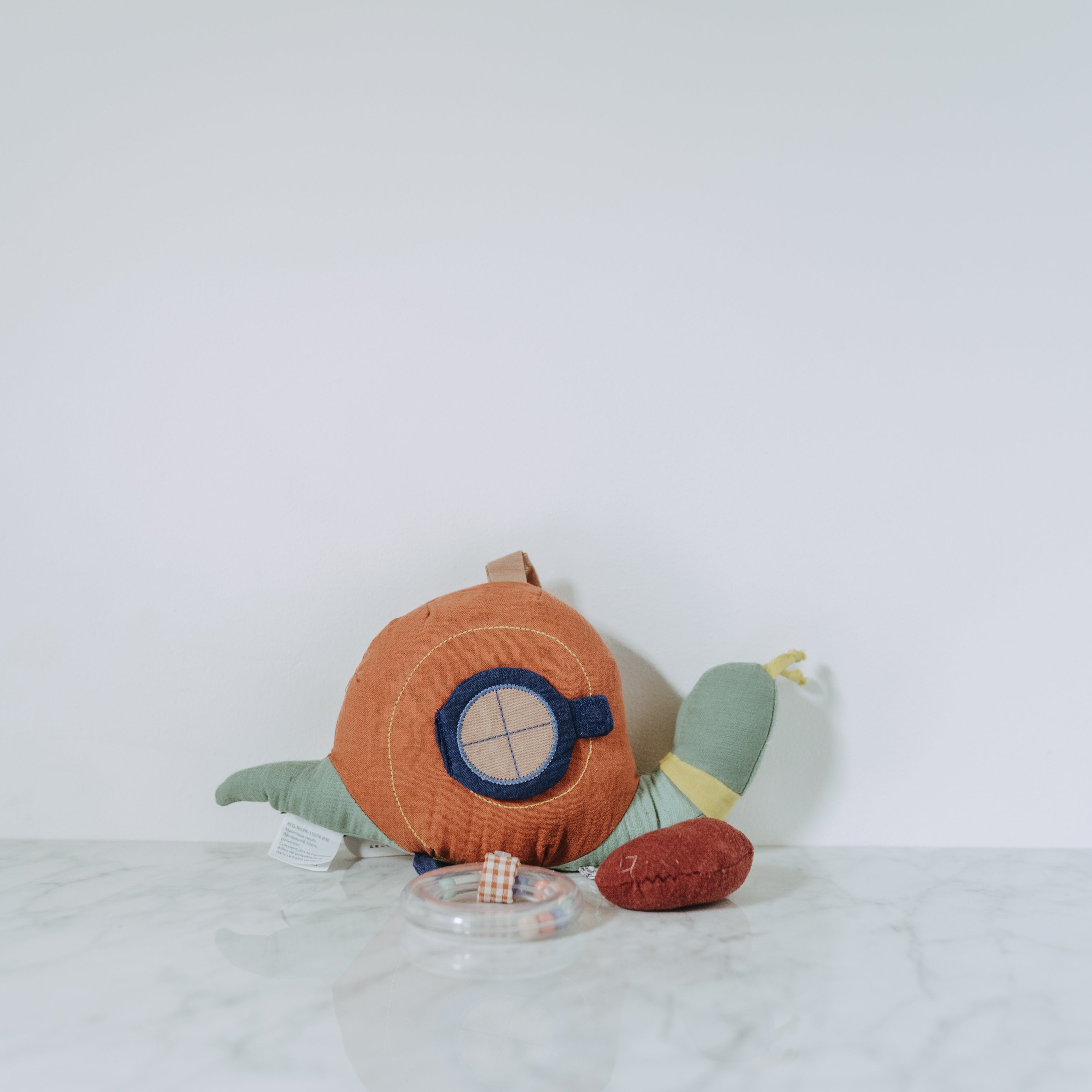 Moulin Roty - Pomme des Bois plush snail toy by Grace and Company Ltd with toy pieces in a clear dish on marble.