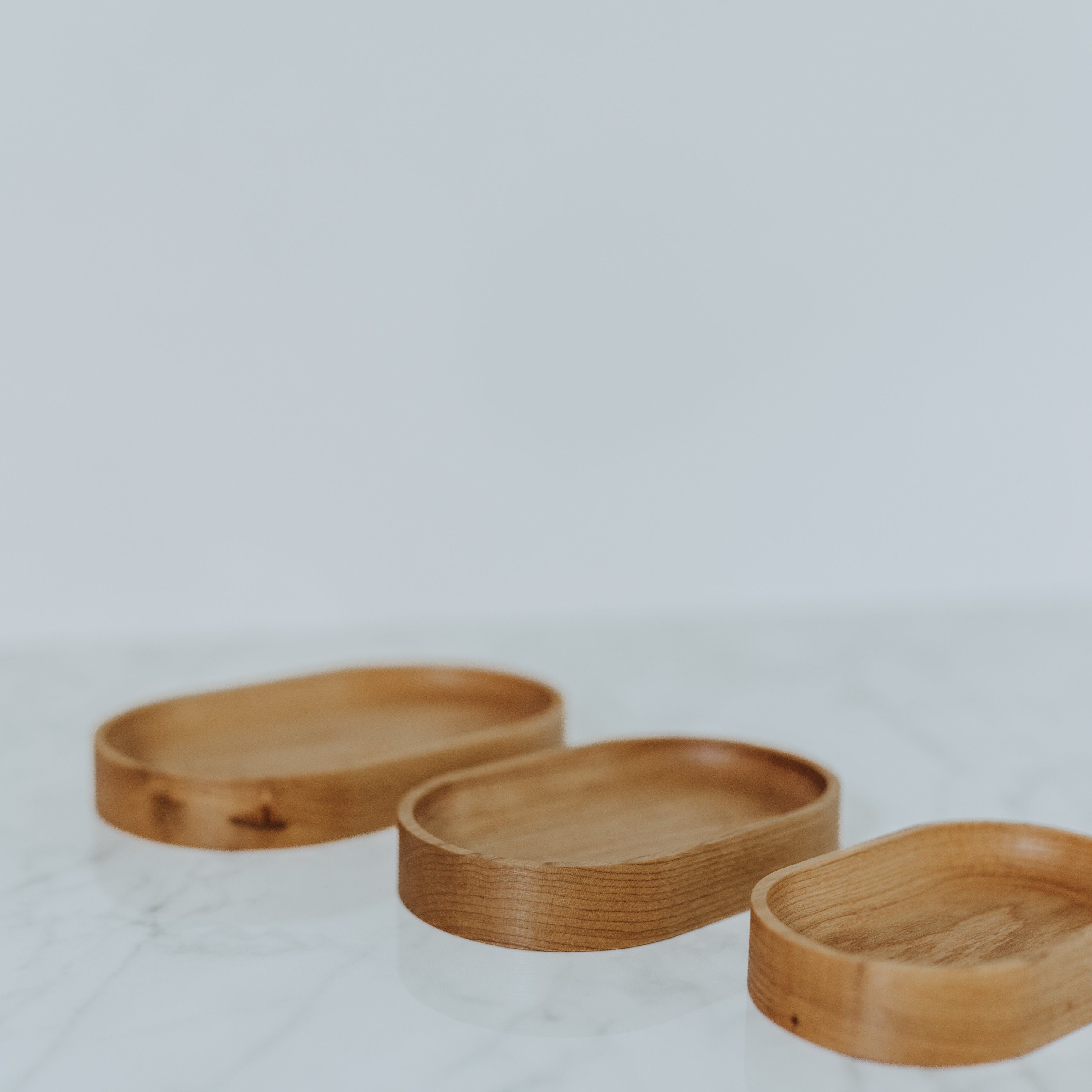 Three Grace & Company Thing Spots wooden trays are displayed on white marble with a plain background.
