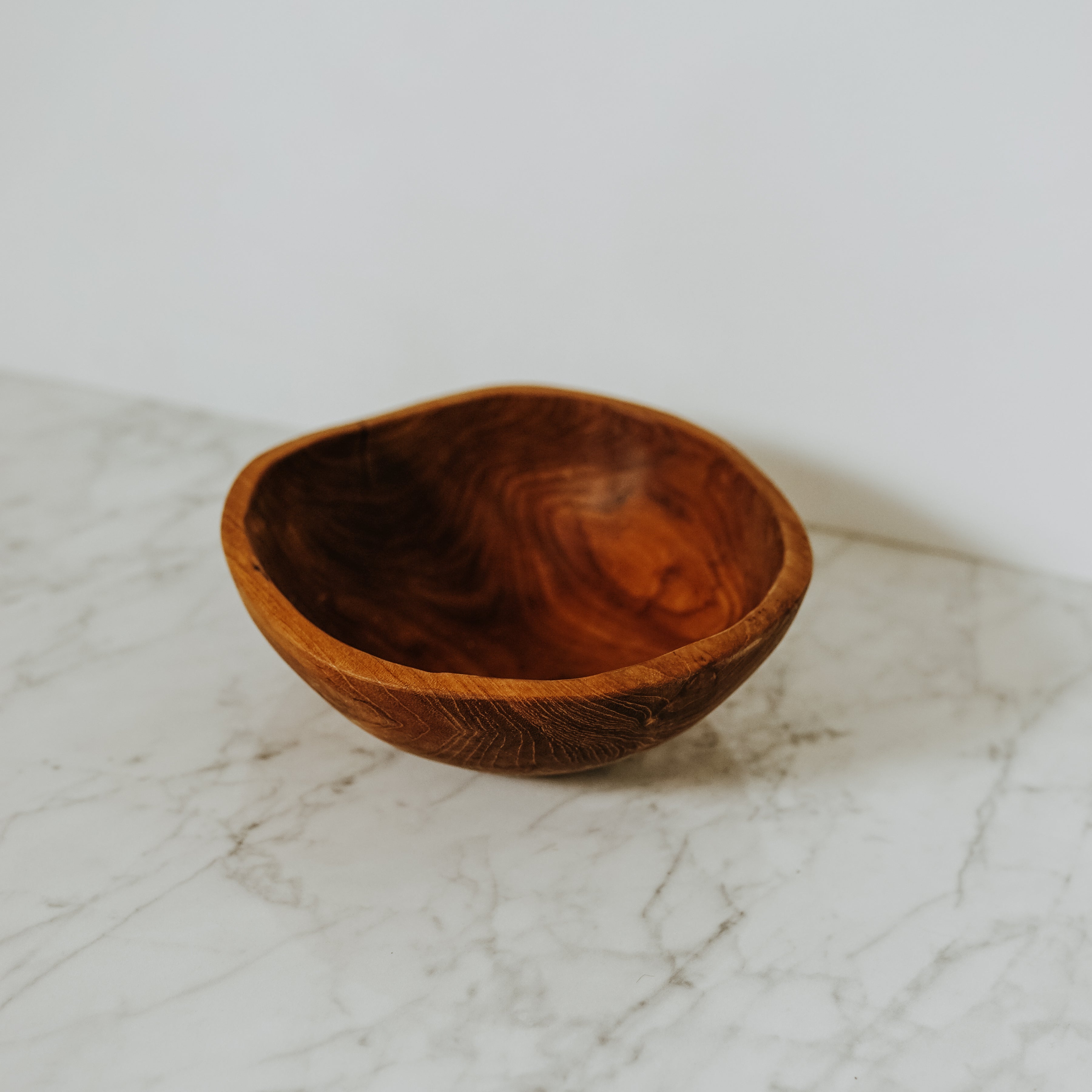 A Grace & Company Live Edge Bowl sits empty on a white marble surface with a plain background.