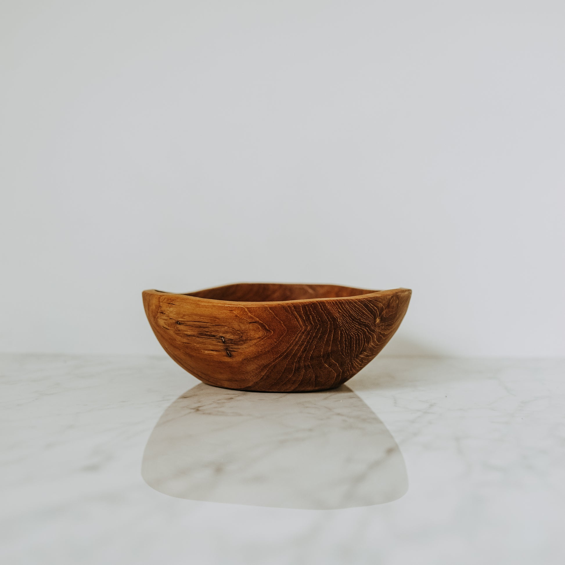 A Grace & Company Live Edge Bowl sits on white marble, set against a plain white background.