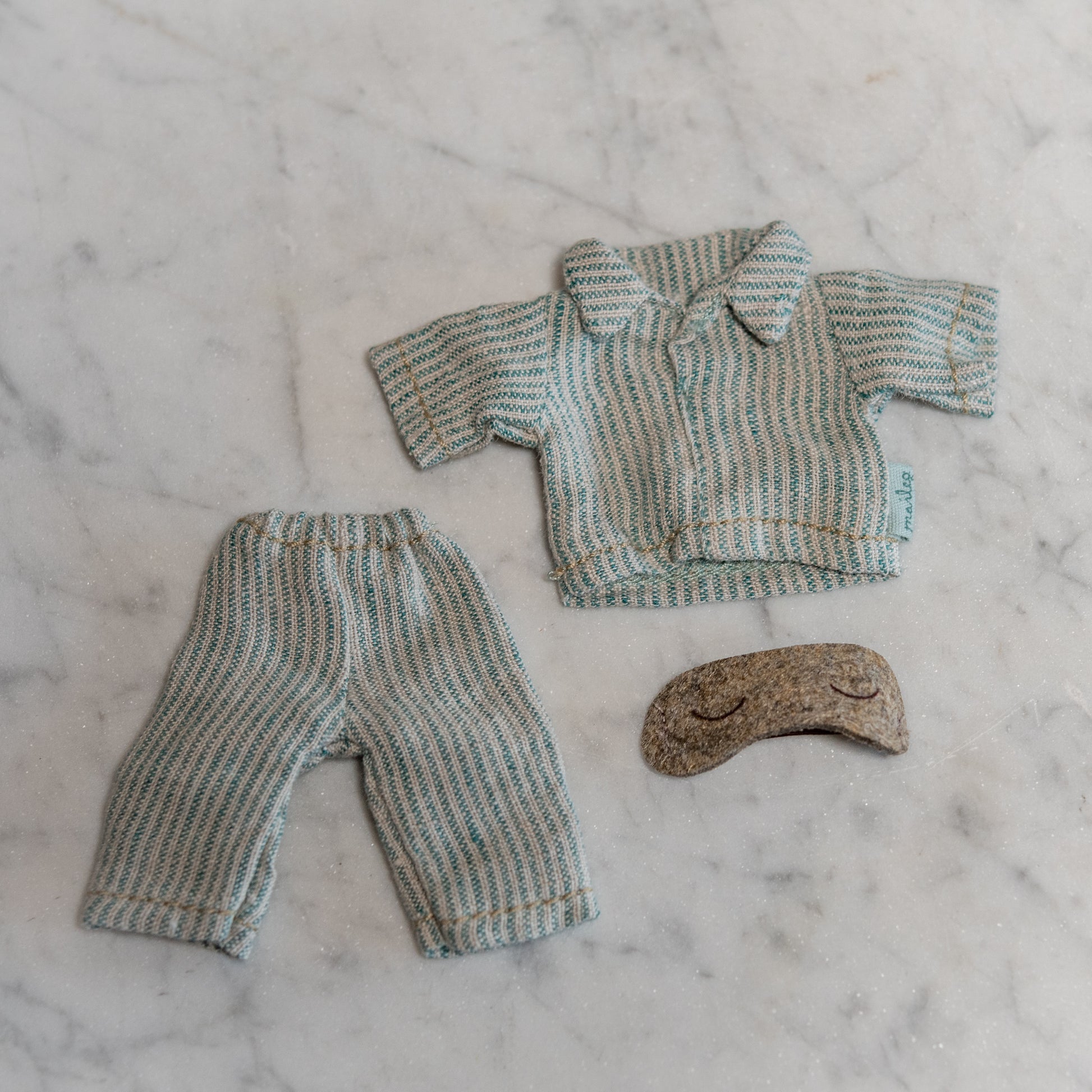 Maileg - Clothing for Mice by Grace & Company, including striped pajamas and a brown sleep mask, on marble.