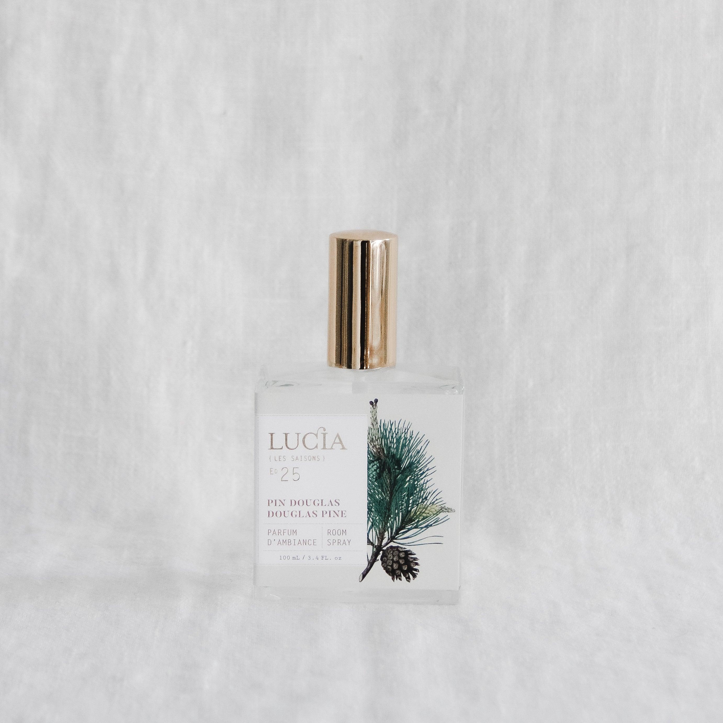 A glass bottle labeled Grace & Company Lucia Les Saisons Douglas Pine Room Spray with a gold cap and pine design.