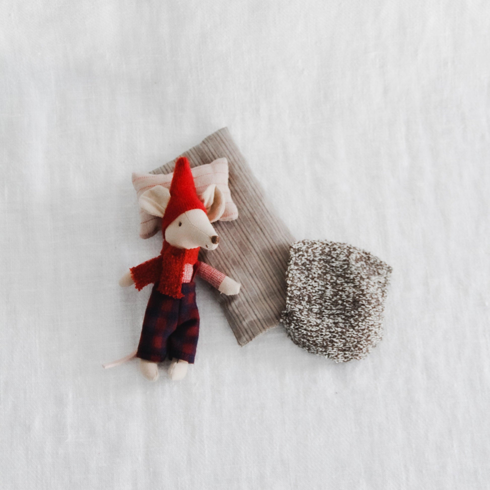The Maileg Christmas Mouse in Matchbox by Grace & Company features Big Brother in pajamas and a red hat, tucked in bed.