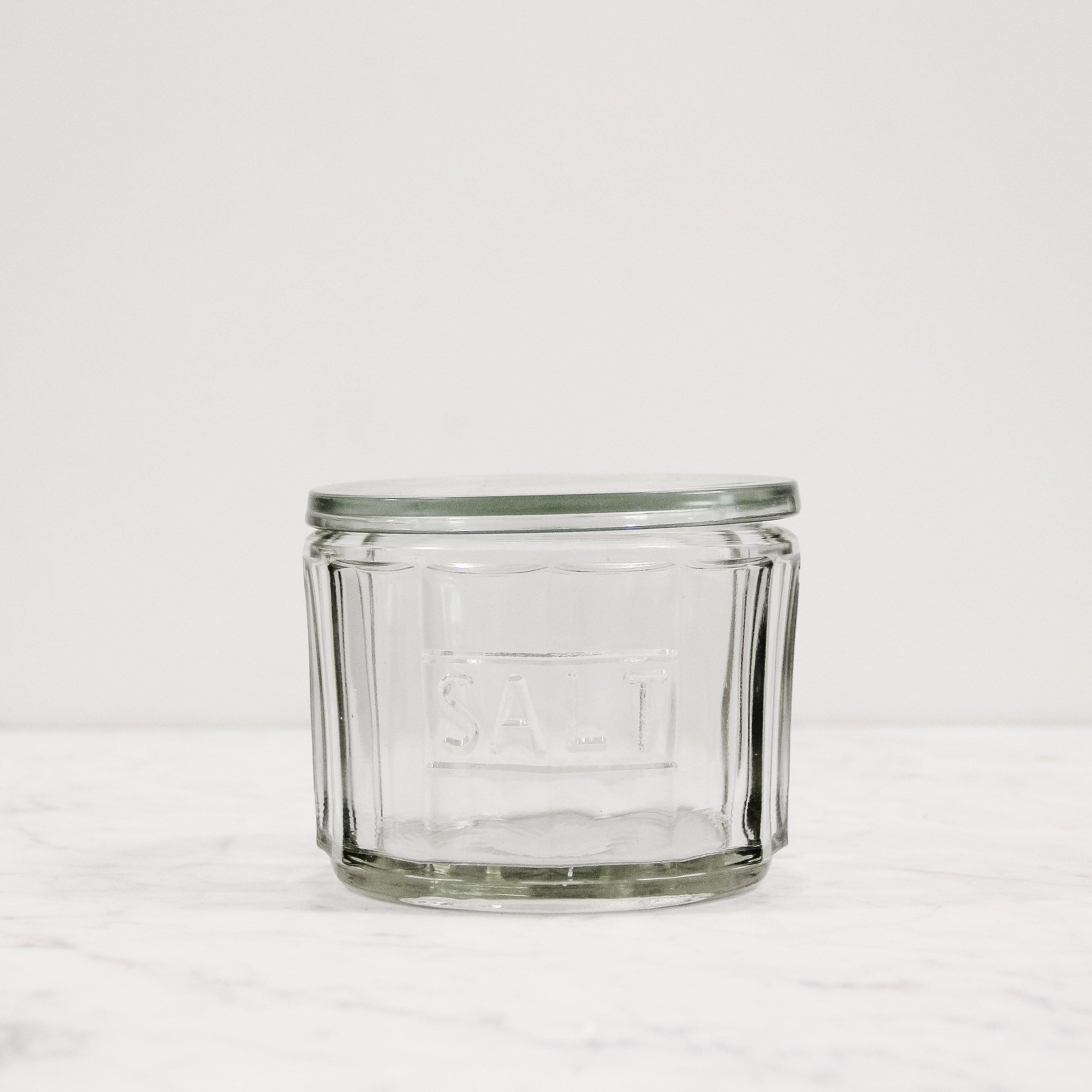 A glass salt cellar that says "salt" embossed in the glass. Has a glass lid