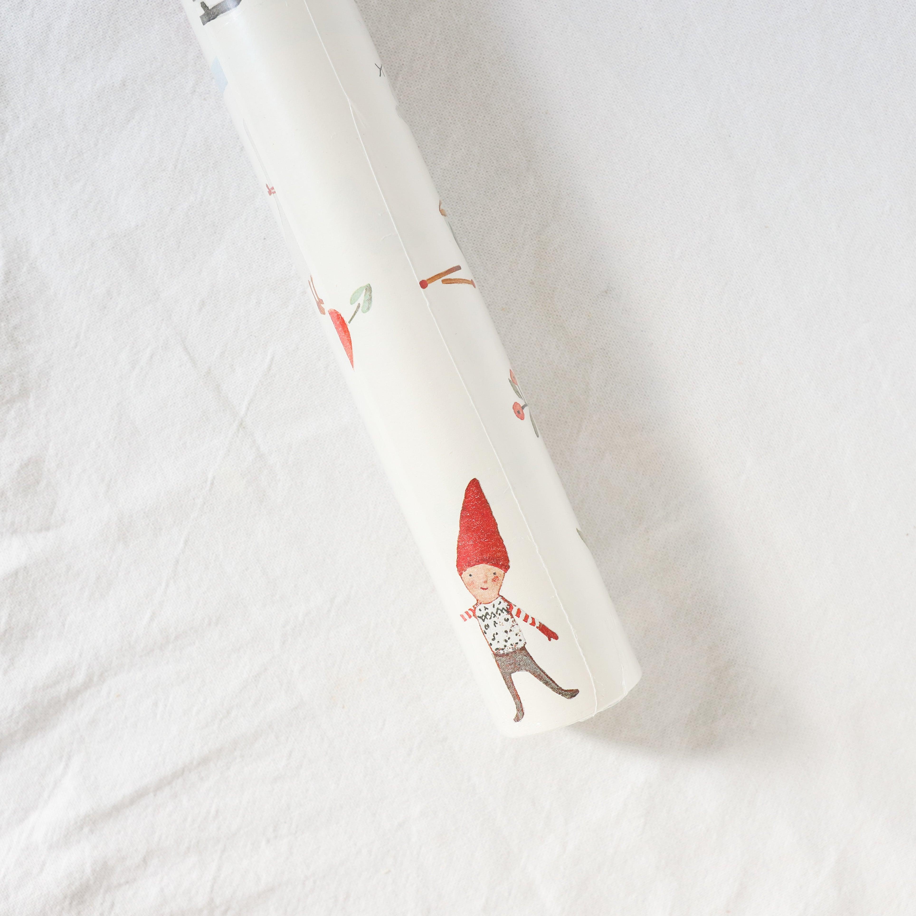 Maileg Wrapping Paper by Grace & Company, featuring a small red-hatted gnome on a white fabric background.